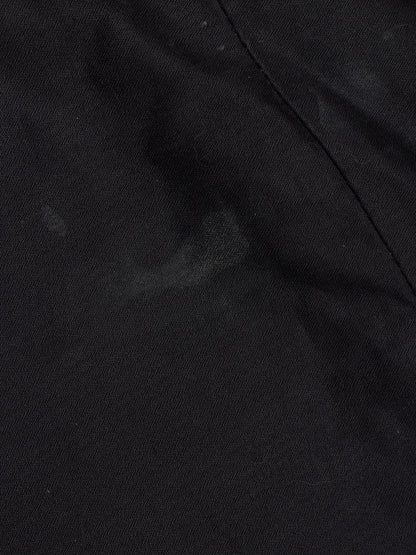 A close-up of black fabric with a visible seam and a slightly mottled texture.