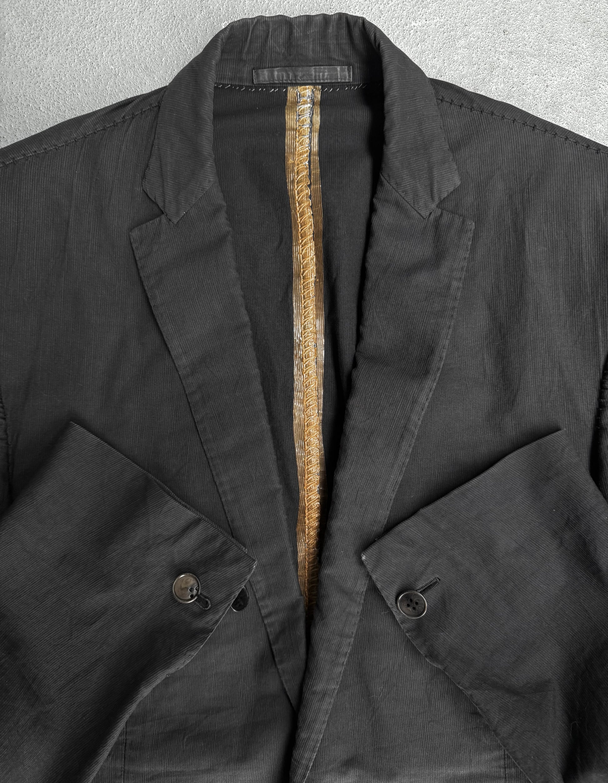 Close-up of a dark jacket with a zipper and button details on a gray background