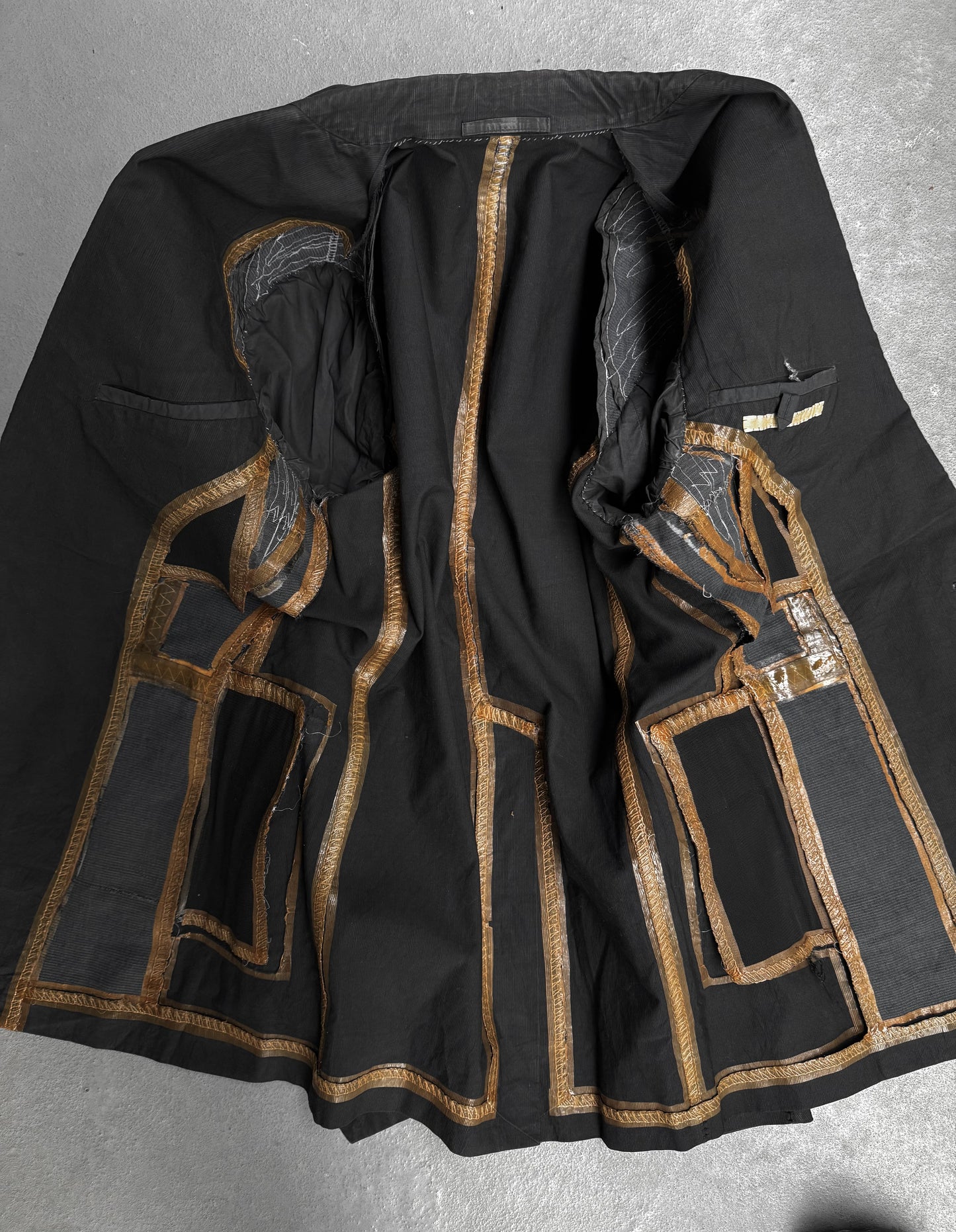 Black garment with gold embroidery on a gray background