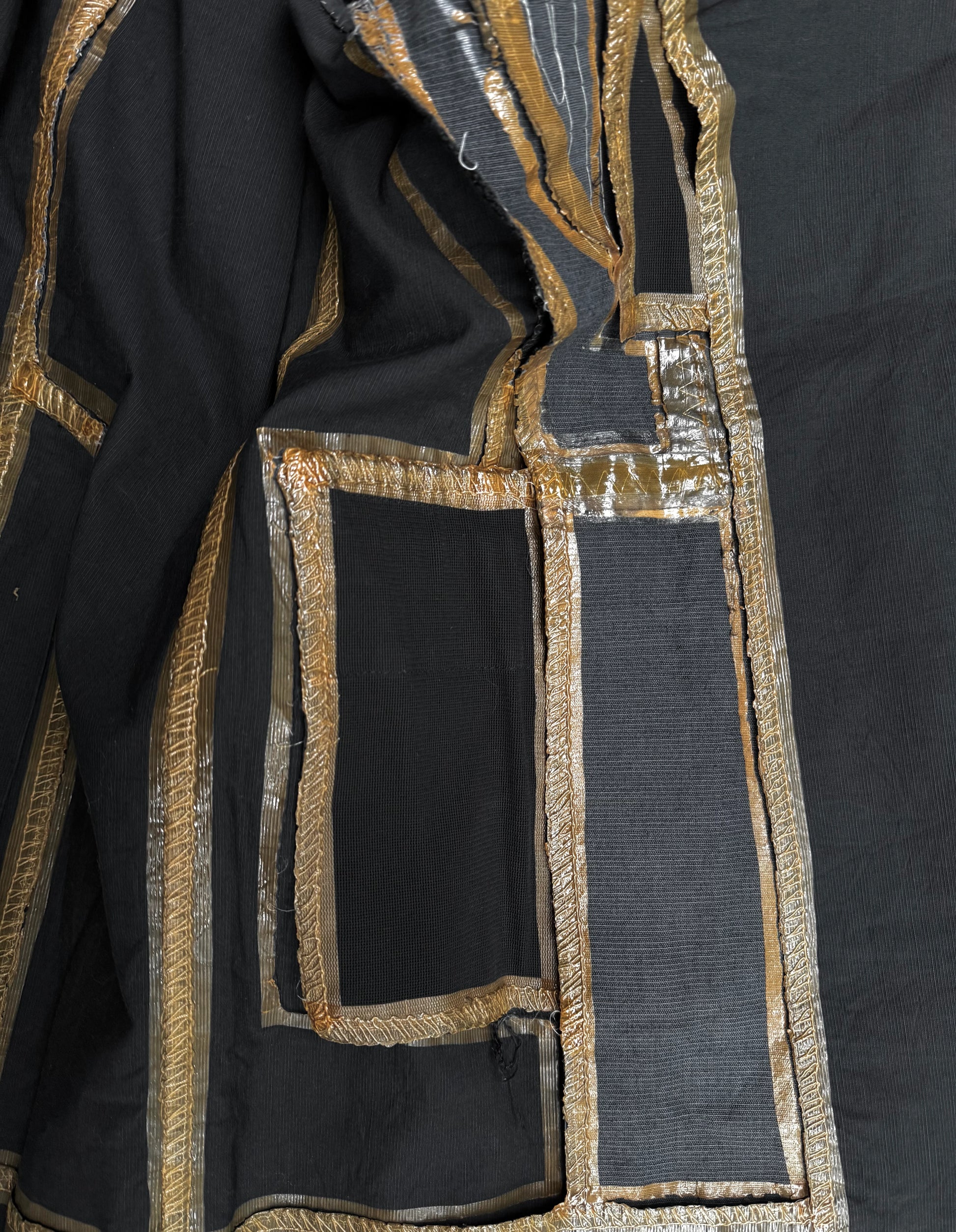 Black fabric with gold and silver embroidery on a dark background