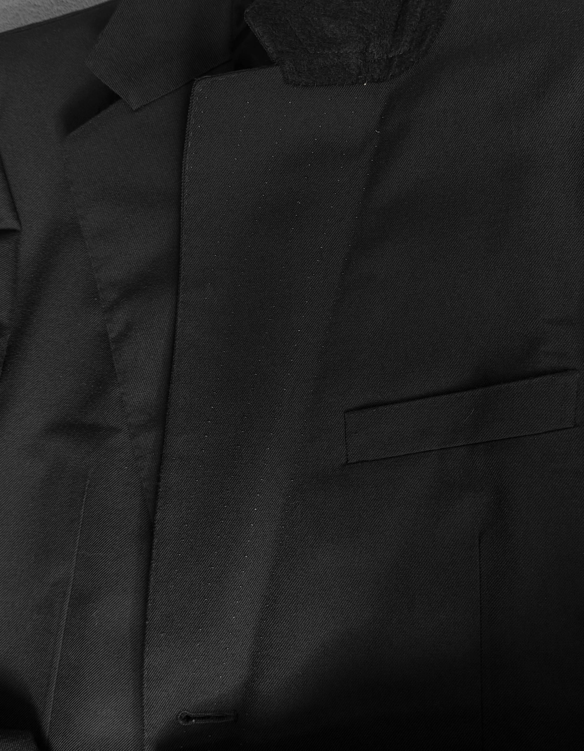 Close-up of a black jacket with a textured hood and pocket detail.