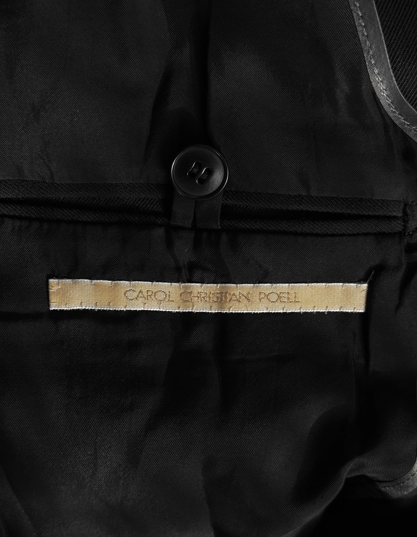 Close-up of a black garment with 'CAROL CHRISTIAN POLO' label.
