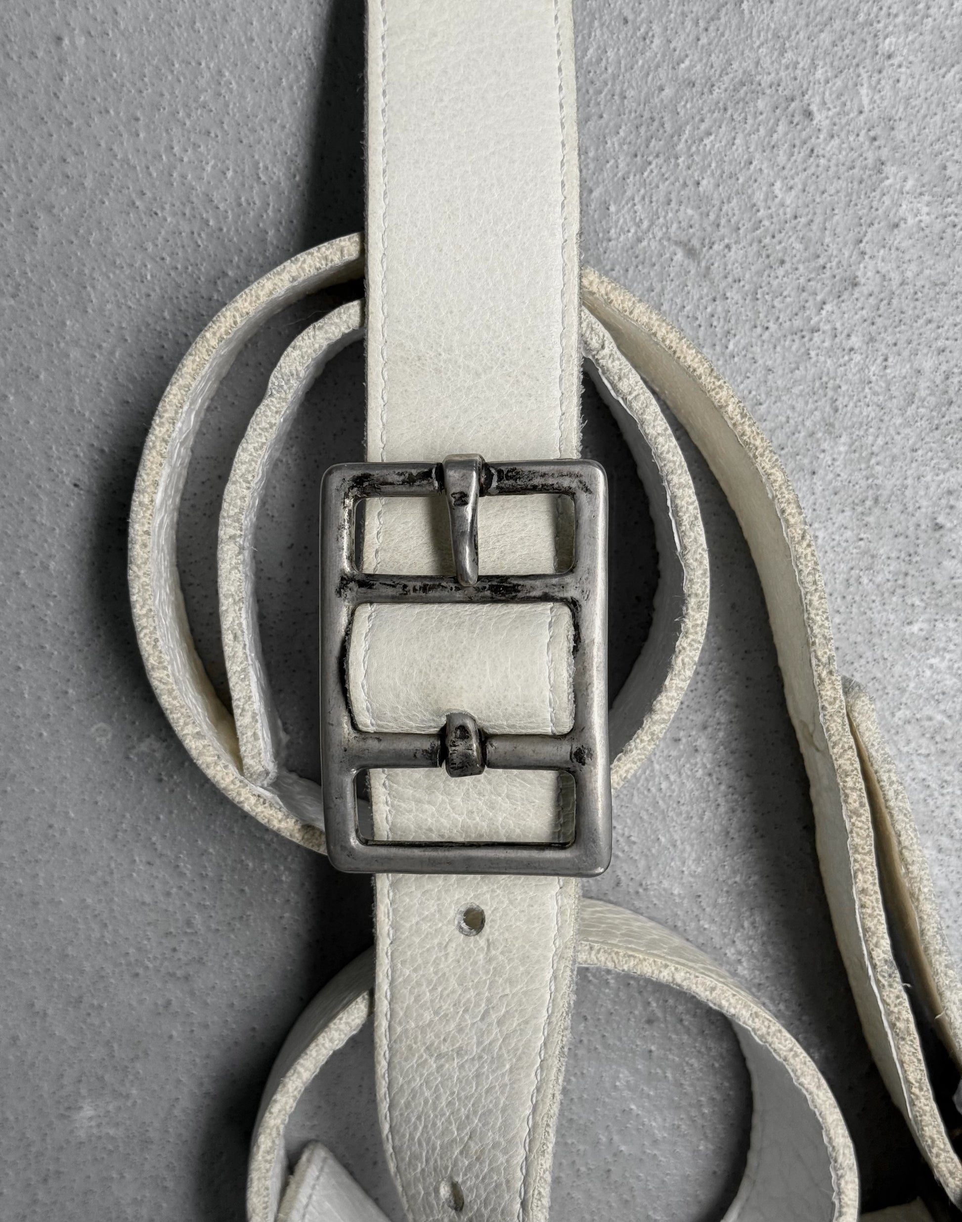 Light gray leather belt with a silver buckle on a gray background