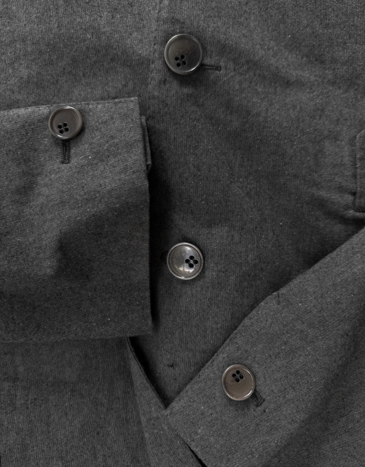 Close-up of a gray coat with buttons on a dark background