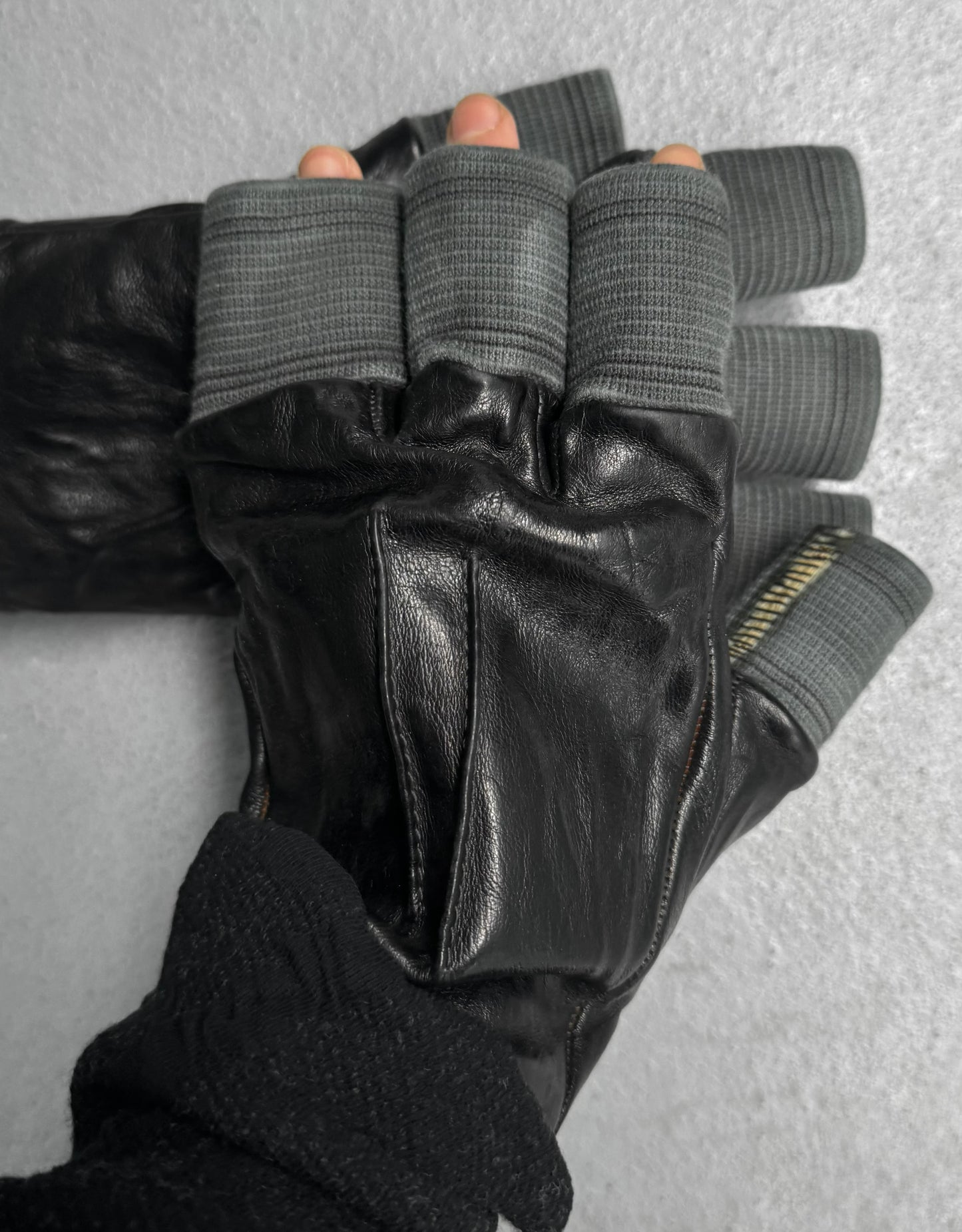 Black leather gloves with gray finger tips on a neutral background