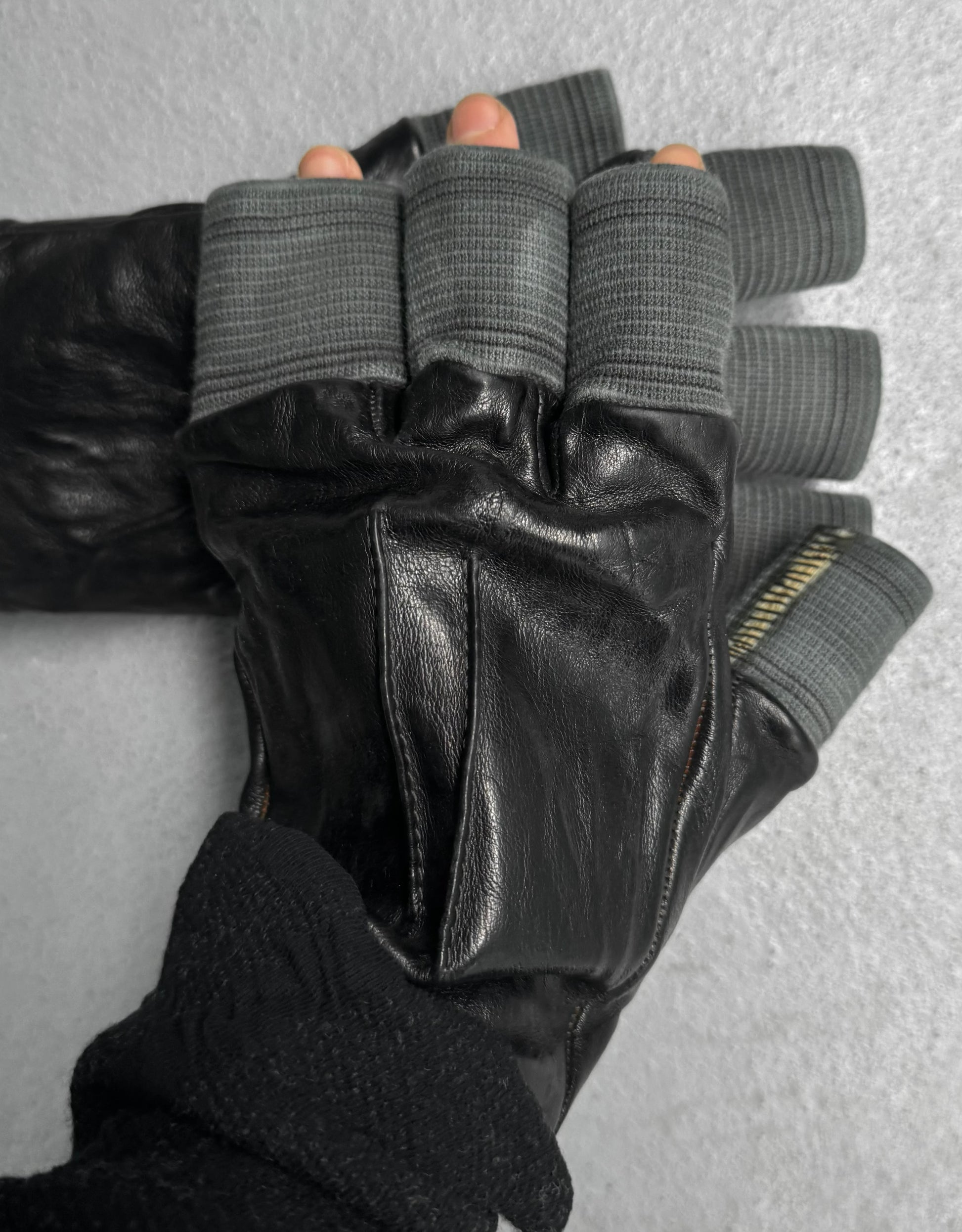 Black leather gloves with gray finger tips on a neutral background