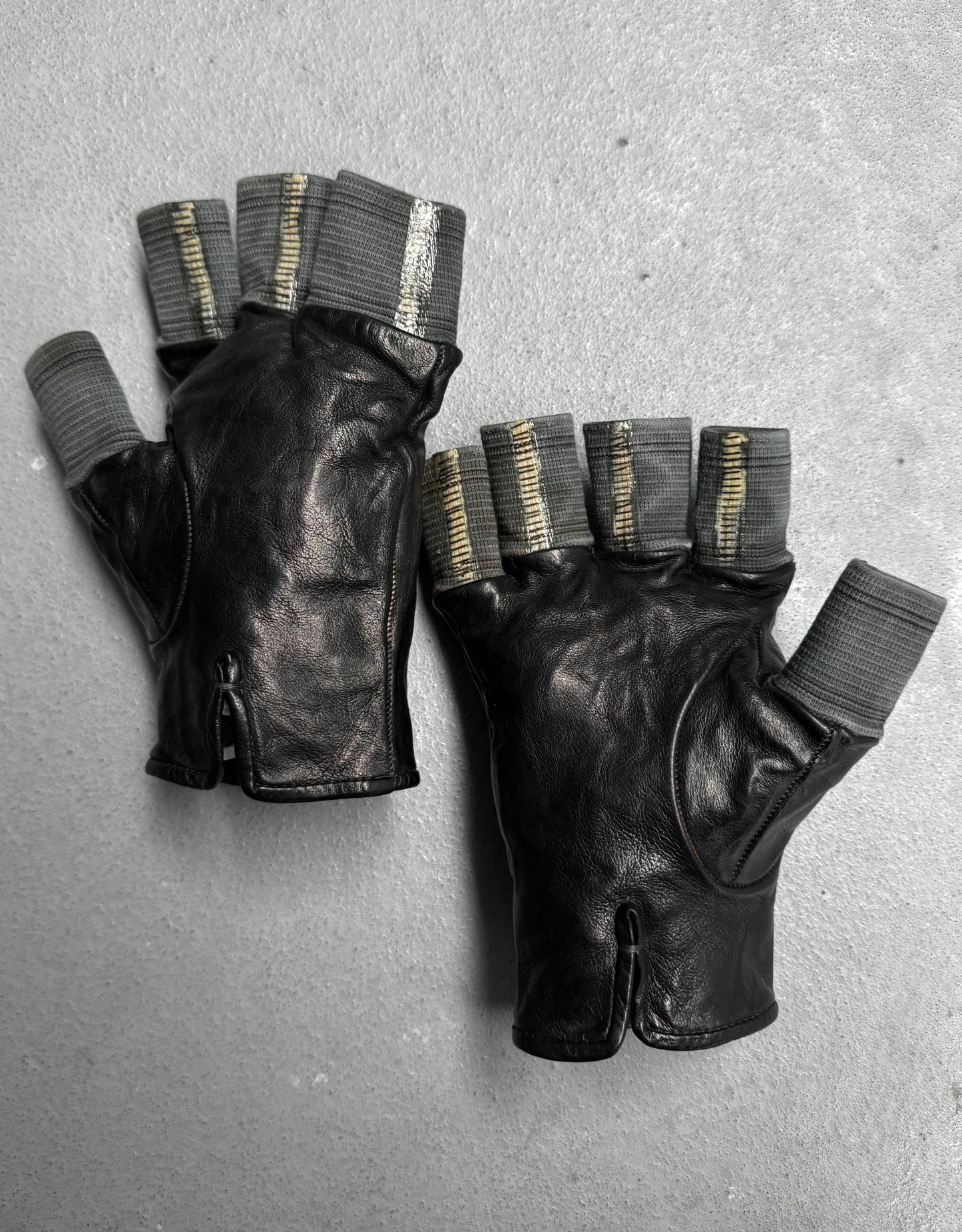 Pair of black leather gloves with gray accents on a gray background