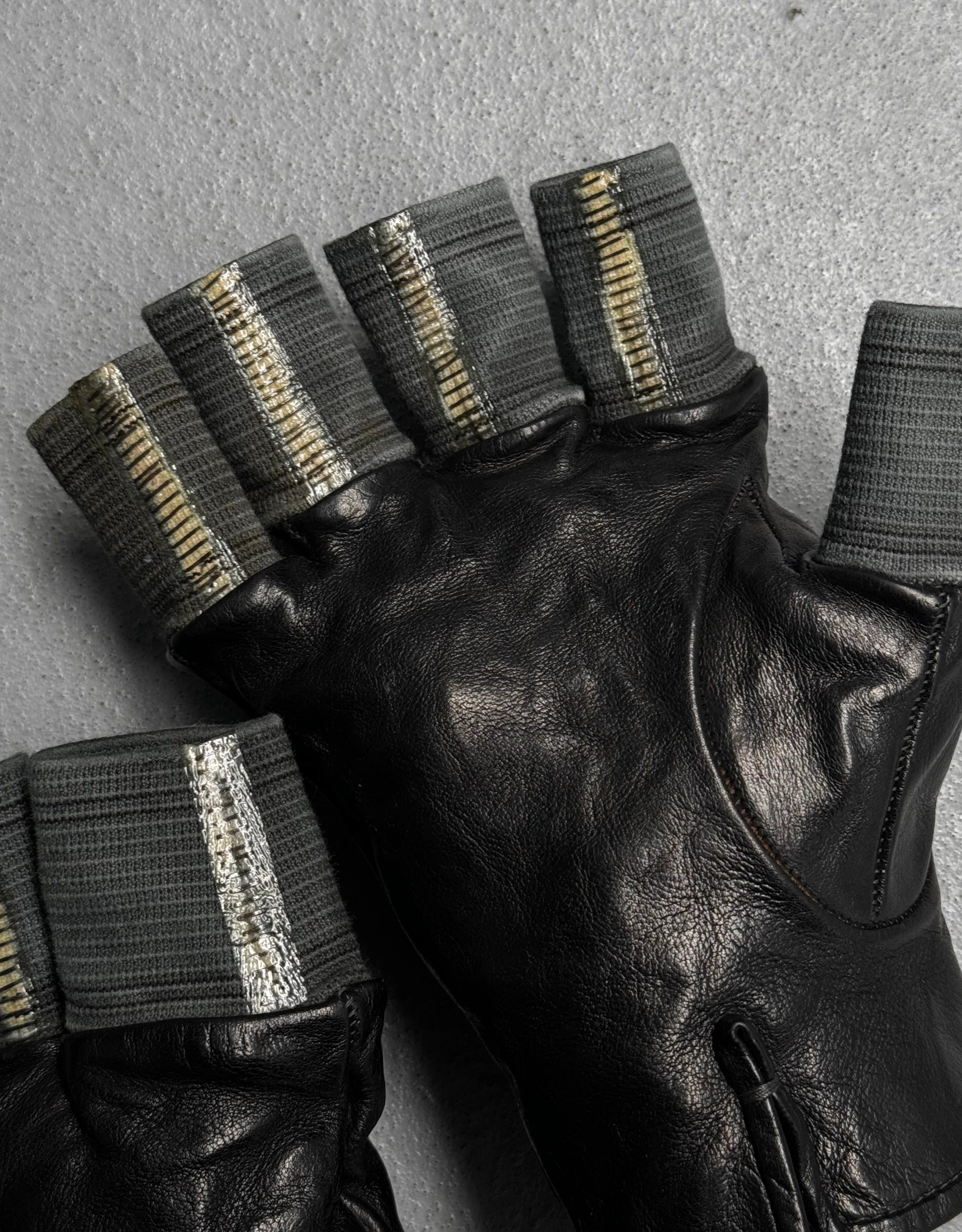 Black leather gloves with metallic accents on a gray background