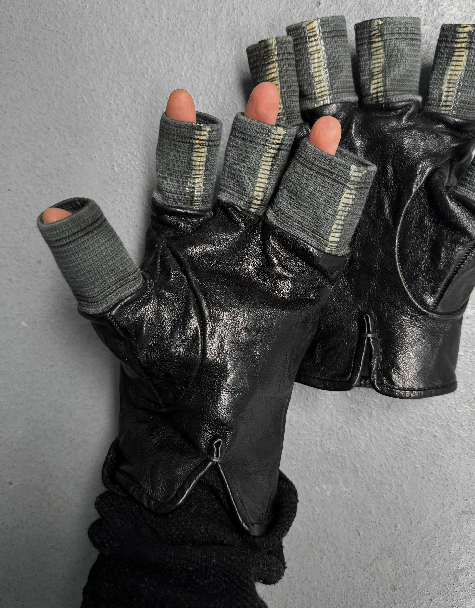 Black leather gloves with gray wristbands on a gray background