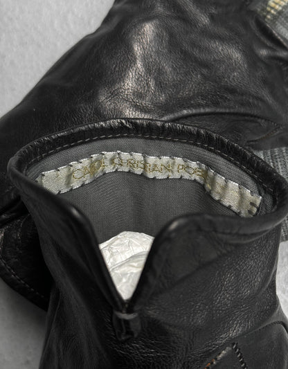 Close-up of black leather glove with brand label on gray background