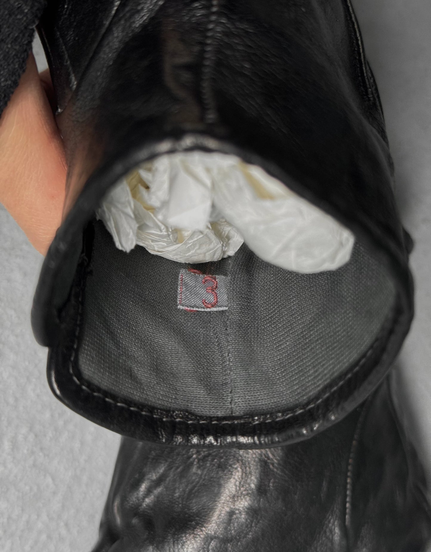 Close-up of a black leather with a white  and visible brand logo.