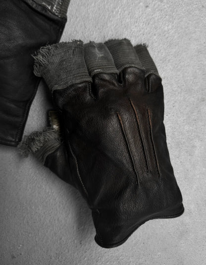 Pair of worn leather gloves on a textured surface