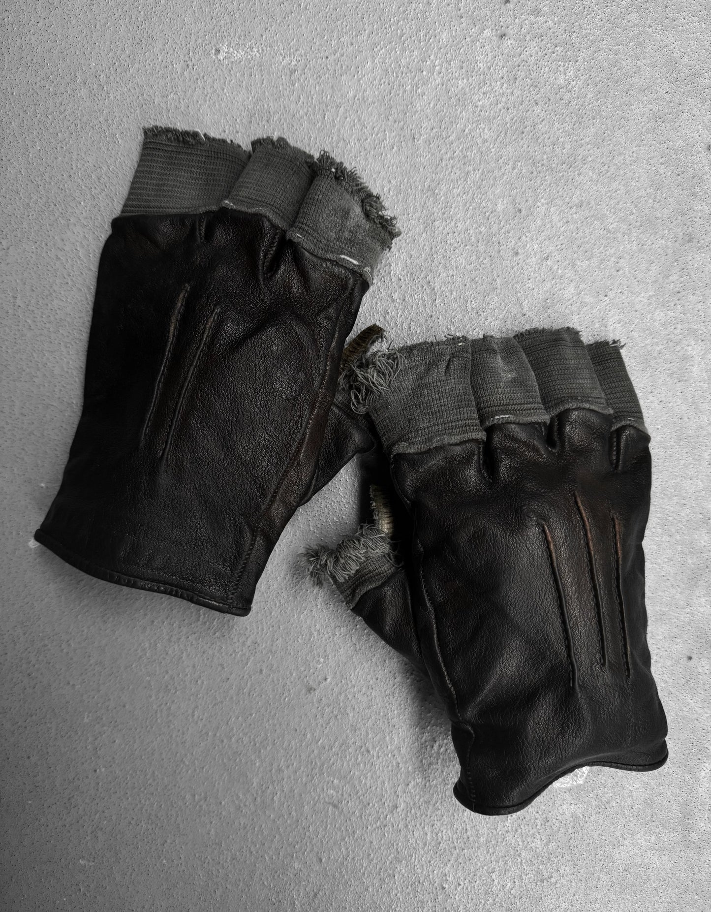 Pair of black leather gloves on a gray surface