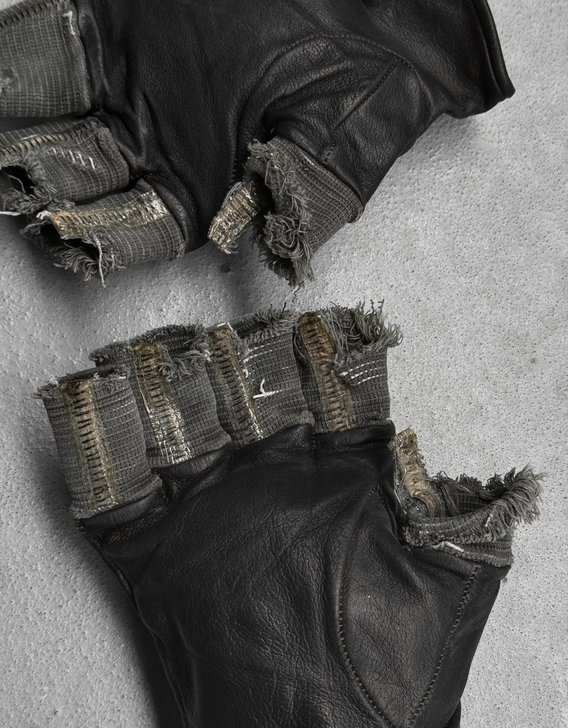 Close-up of black gloves with textured palm and fingers on a gray background