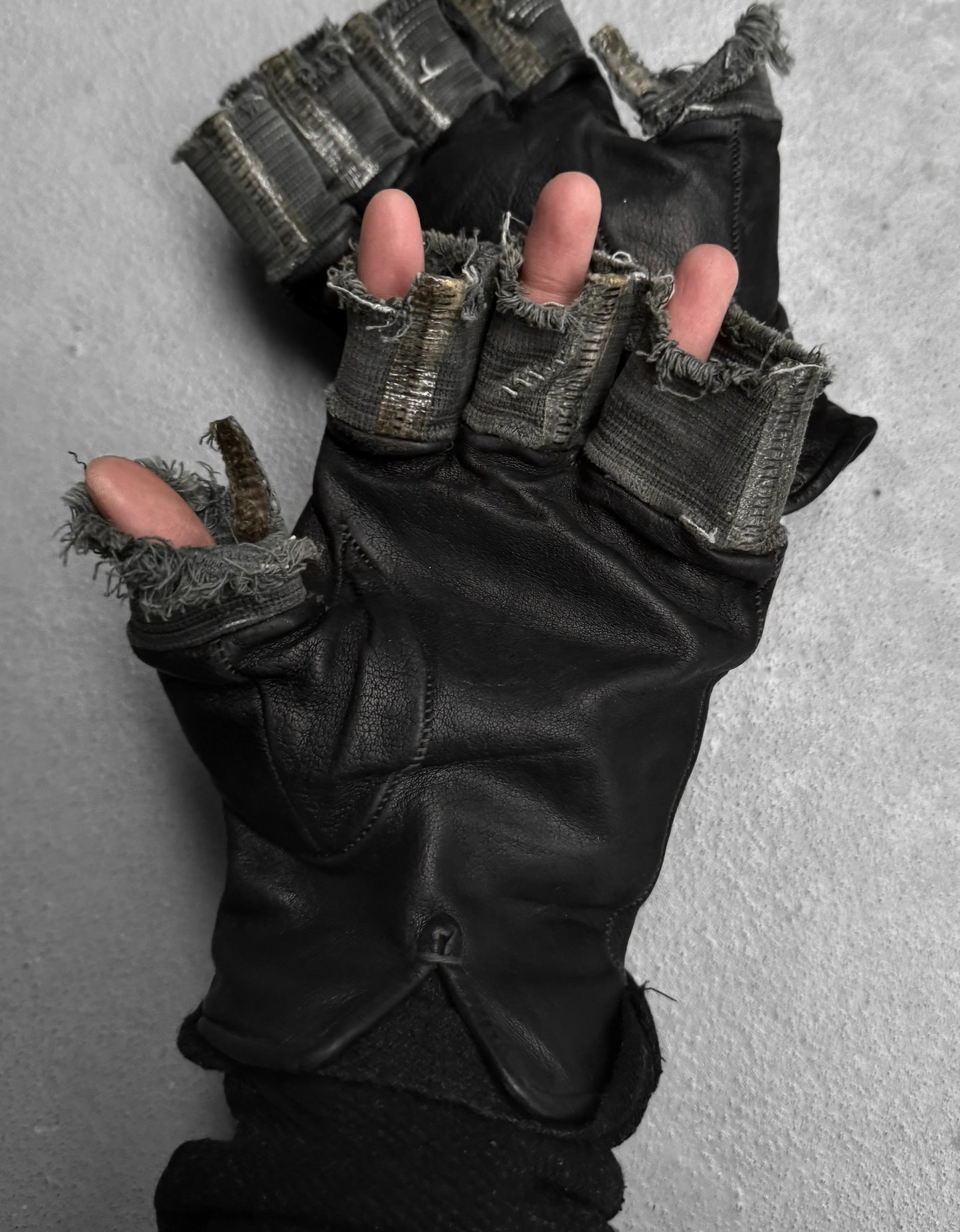 Black gloves with frayed edges on a gray background