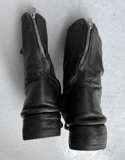 Pair of black leather boots with zippers on a light gray background