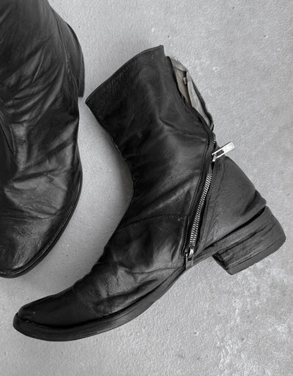Black leather boots with zippers on a gray surface