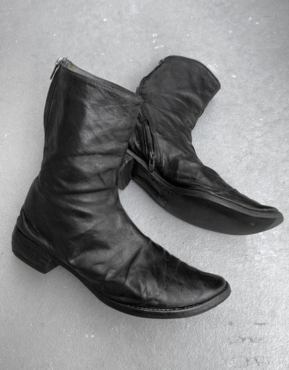 Pair of black leather boots on a gray surface