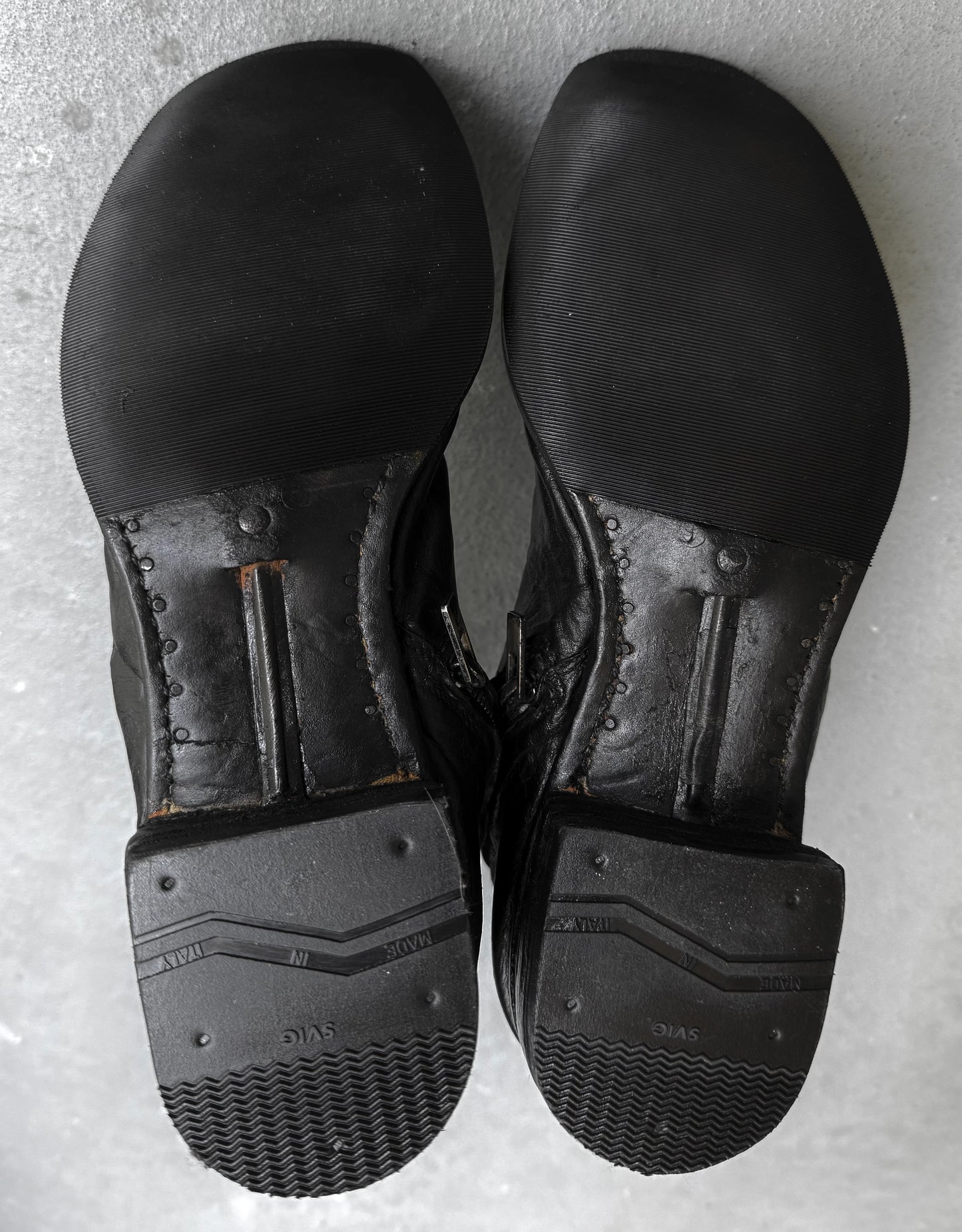 Pair of black leather shoes on a gray surface