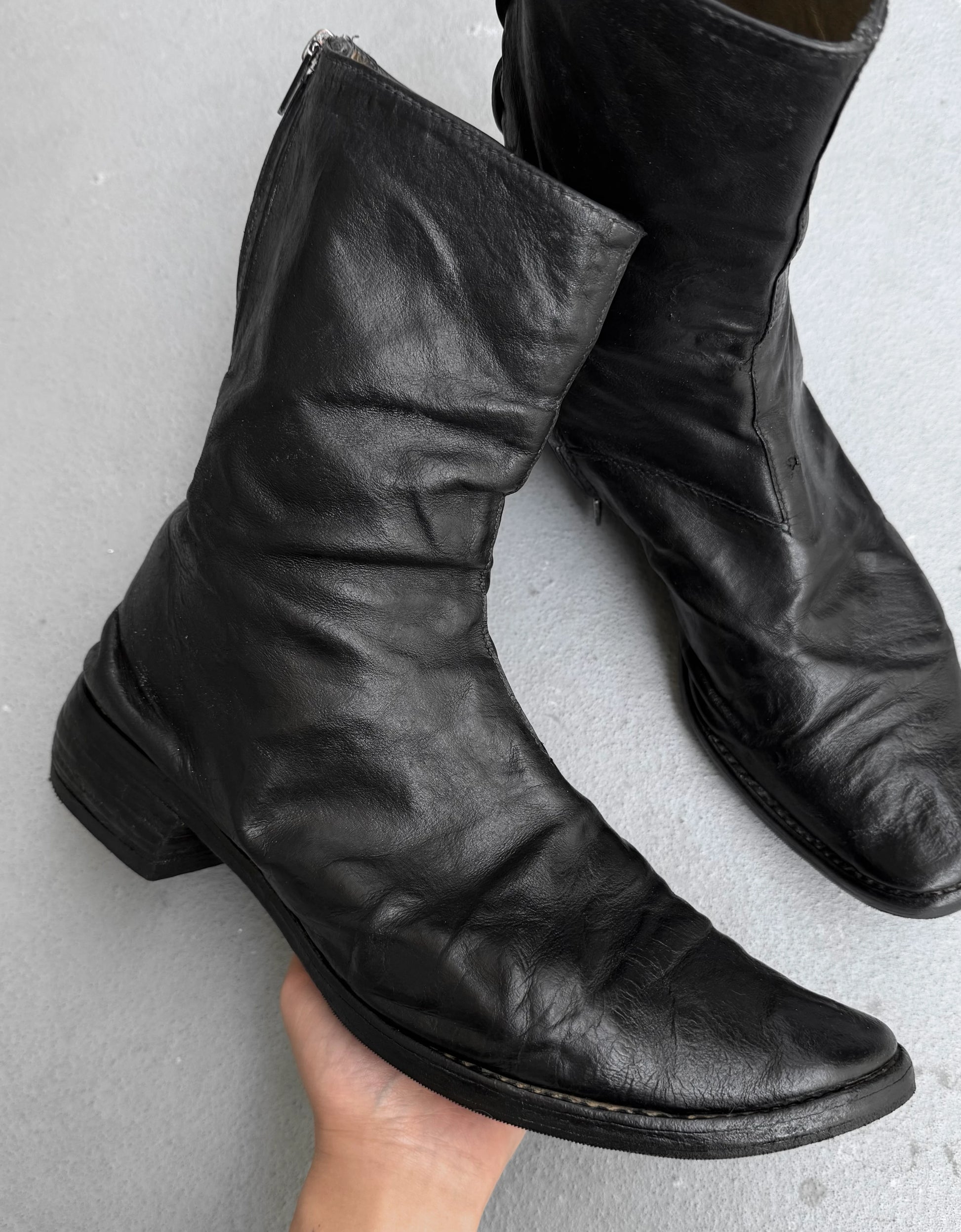Pair of black leather boots on a gray background