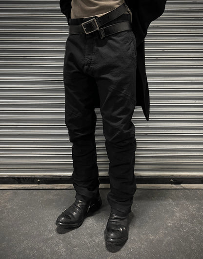 Person wearing black pants and shoes standing in front of a metallic shutter.