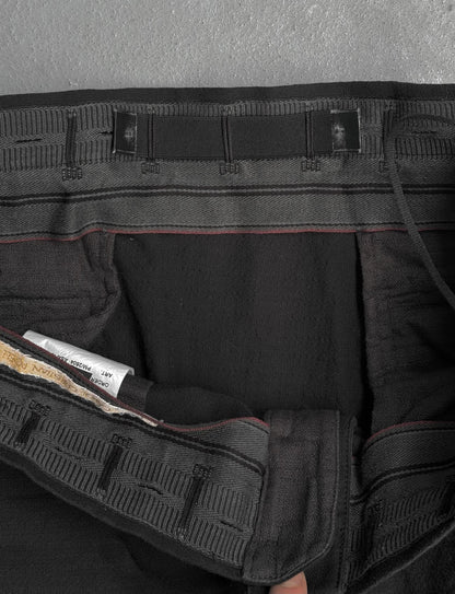 Close-up of a black tactical belt with multiple straps on a gray background
