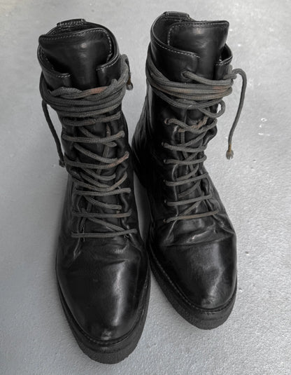 Pair of black leather boots with laces on a light gray background