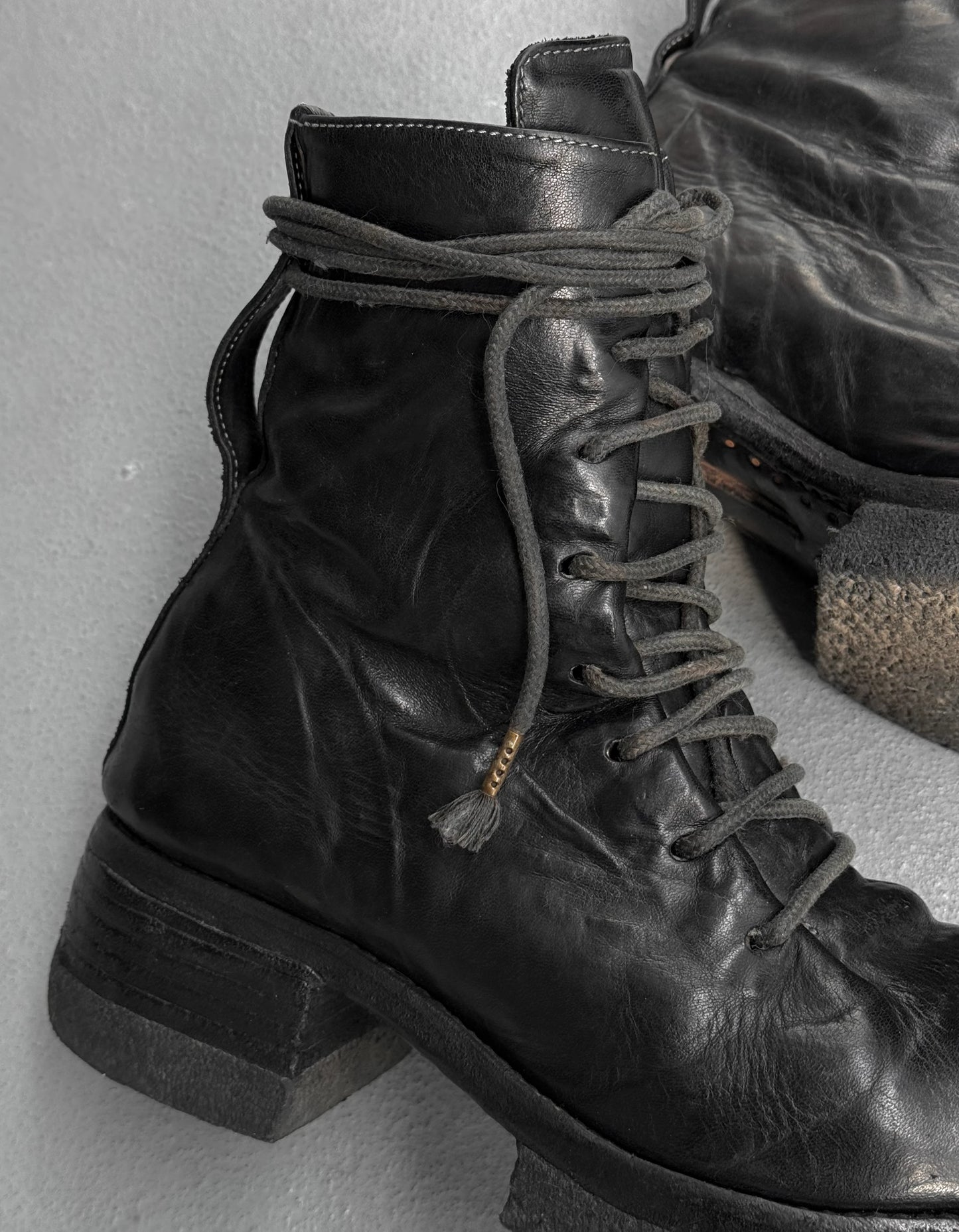 Close-up of black leather boots with laces on a light gray background