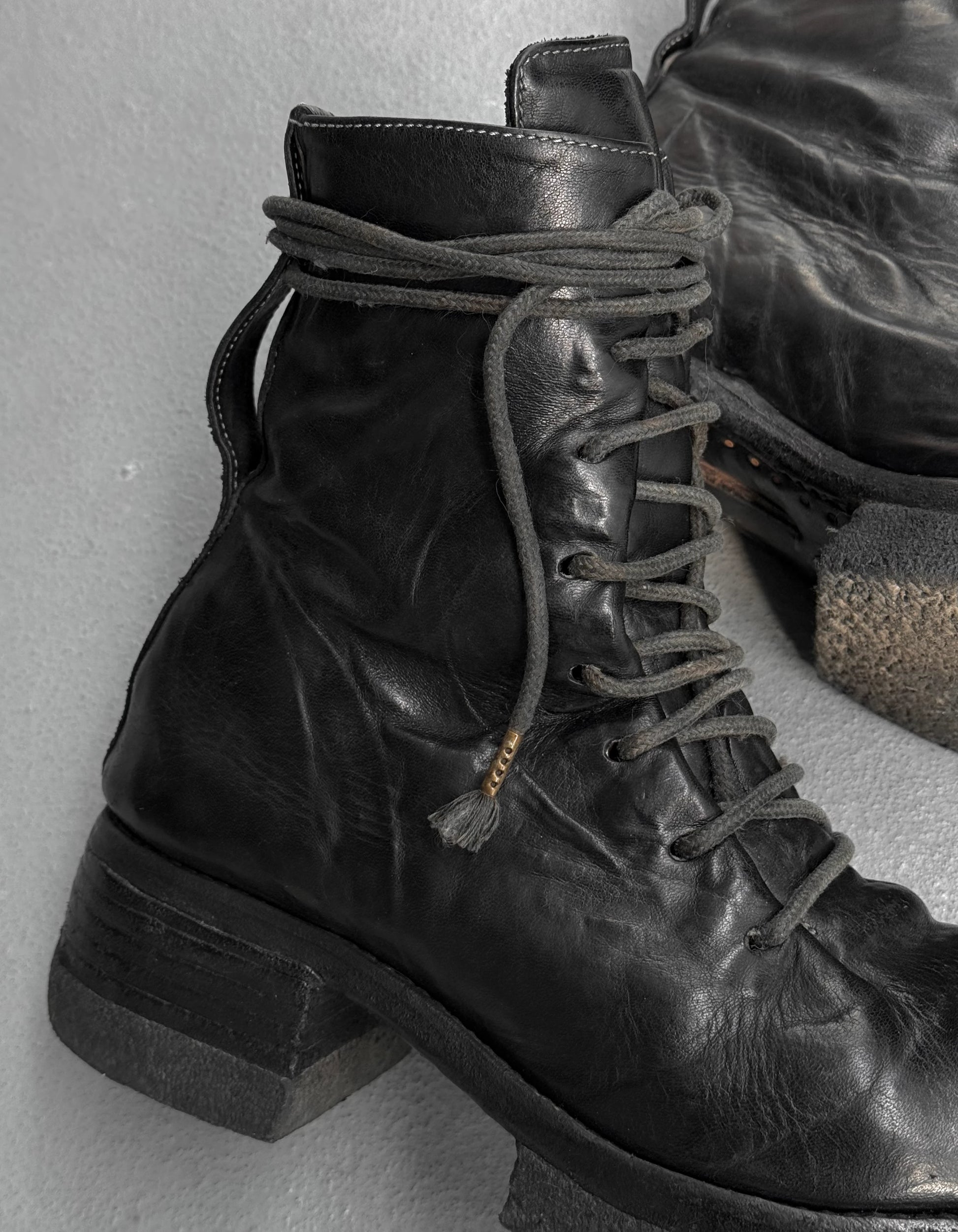 Close-up of black leather boots with laces on a light gray background