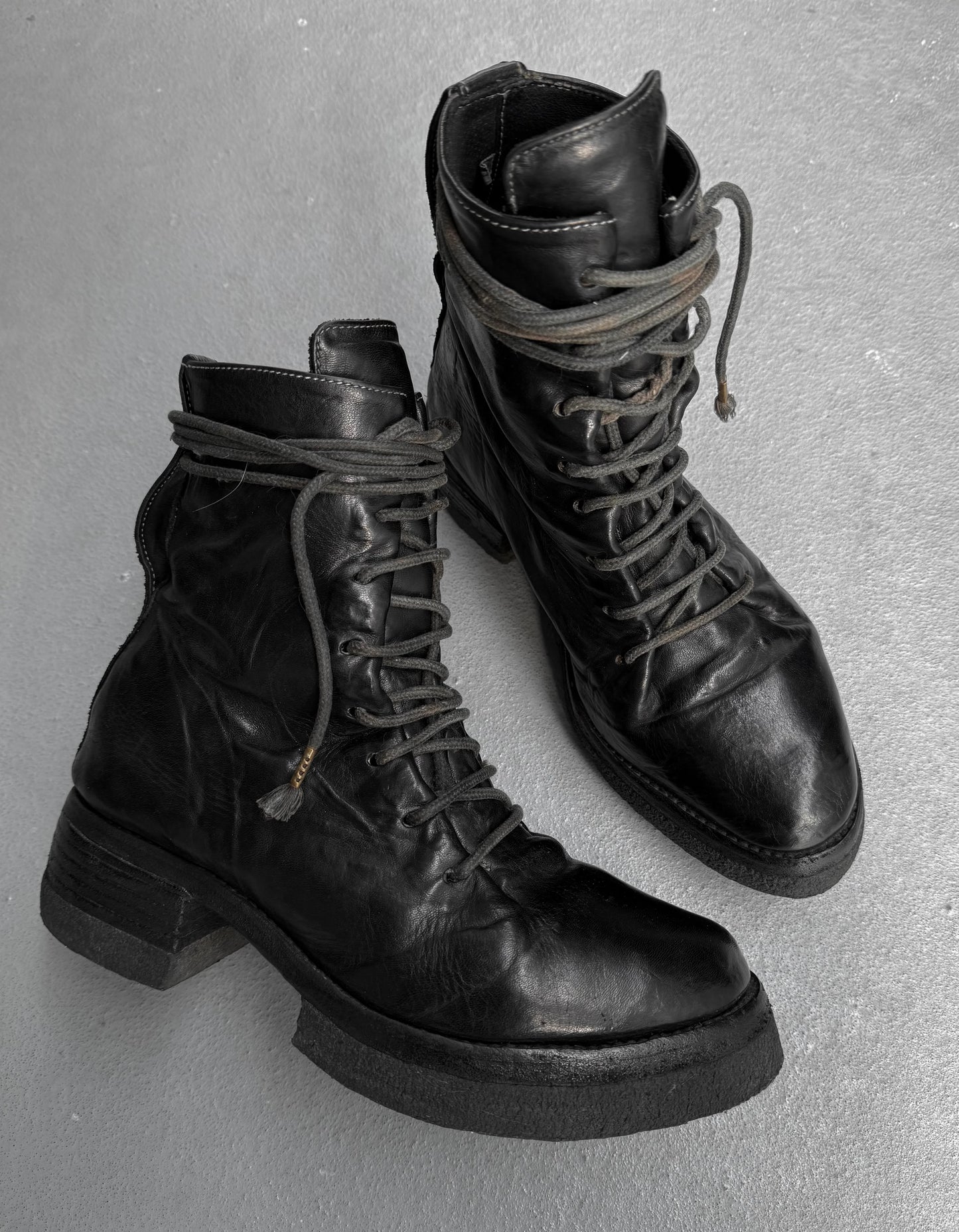 Pair of black leather boots with thick soles on a gray background
