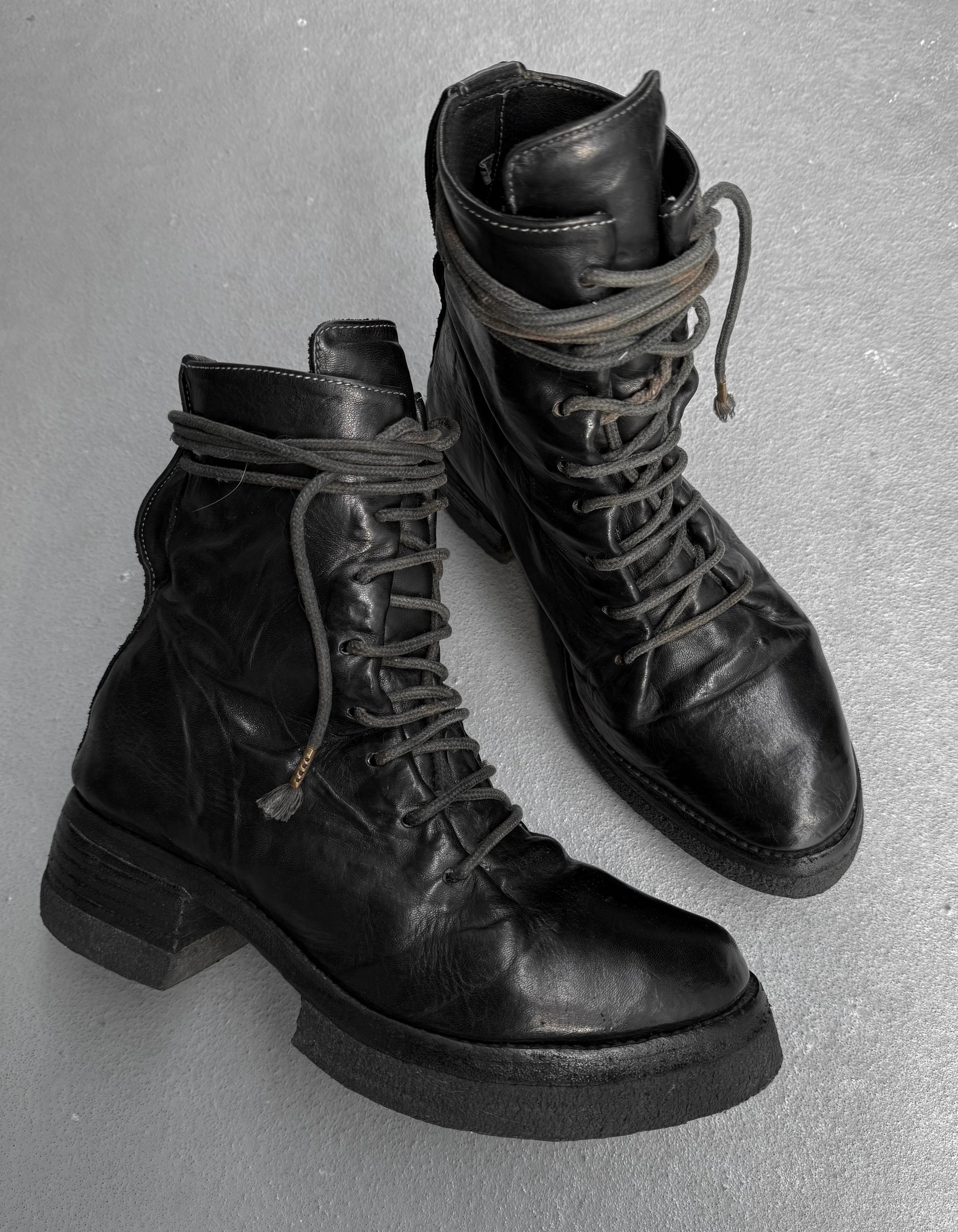 Pair of black leather boots with thick soles on a gray background