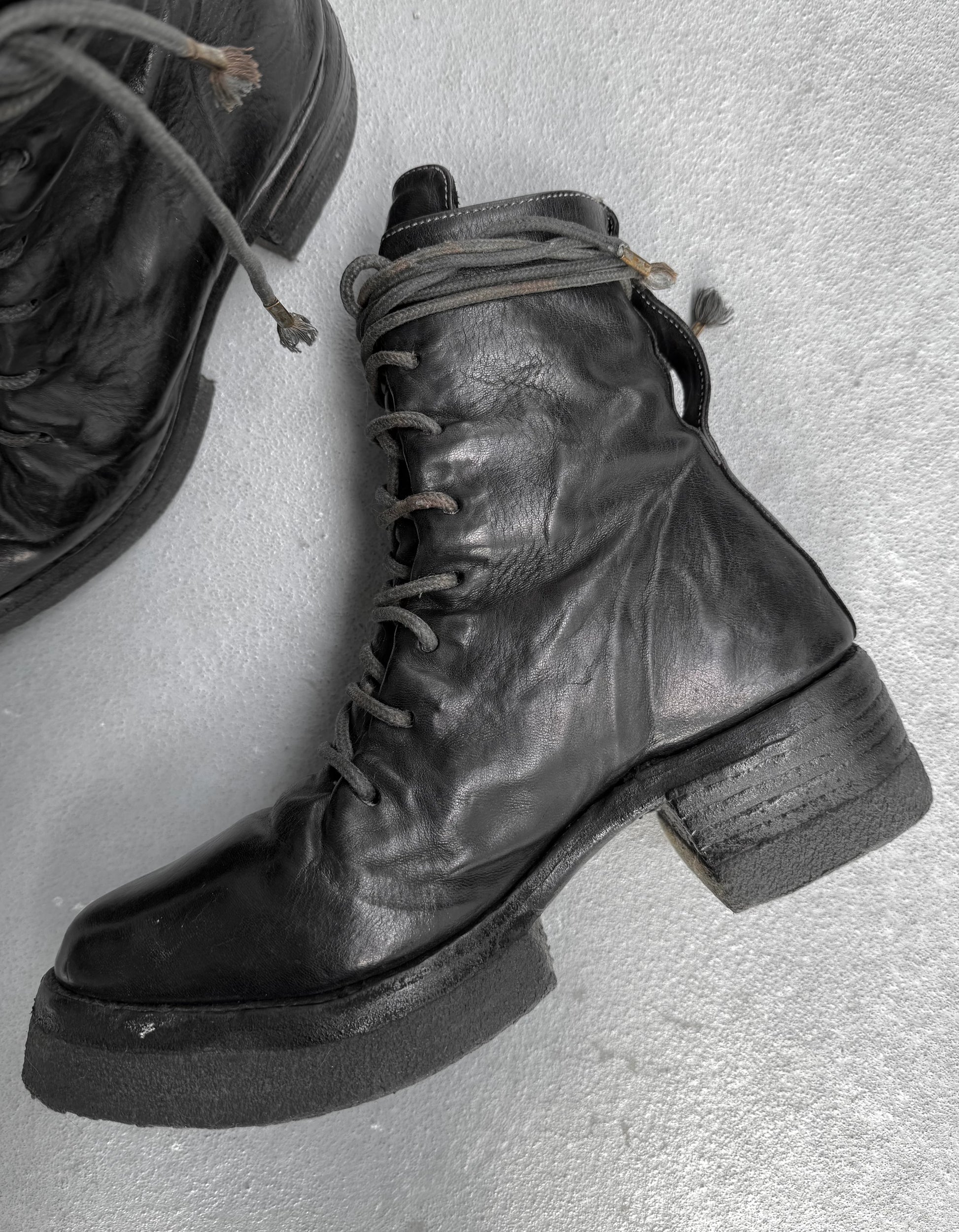Black leather boot with a block heel on a light gray background