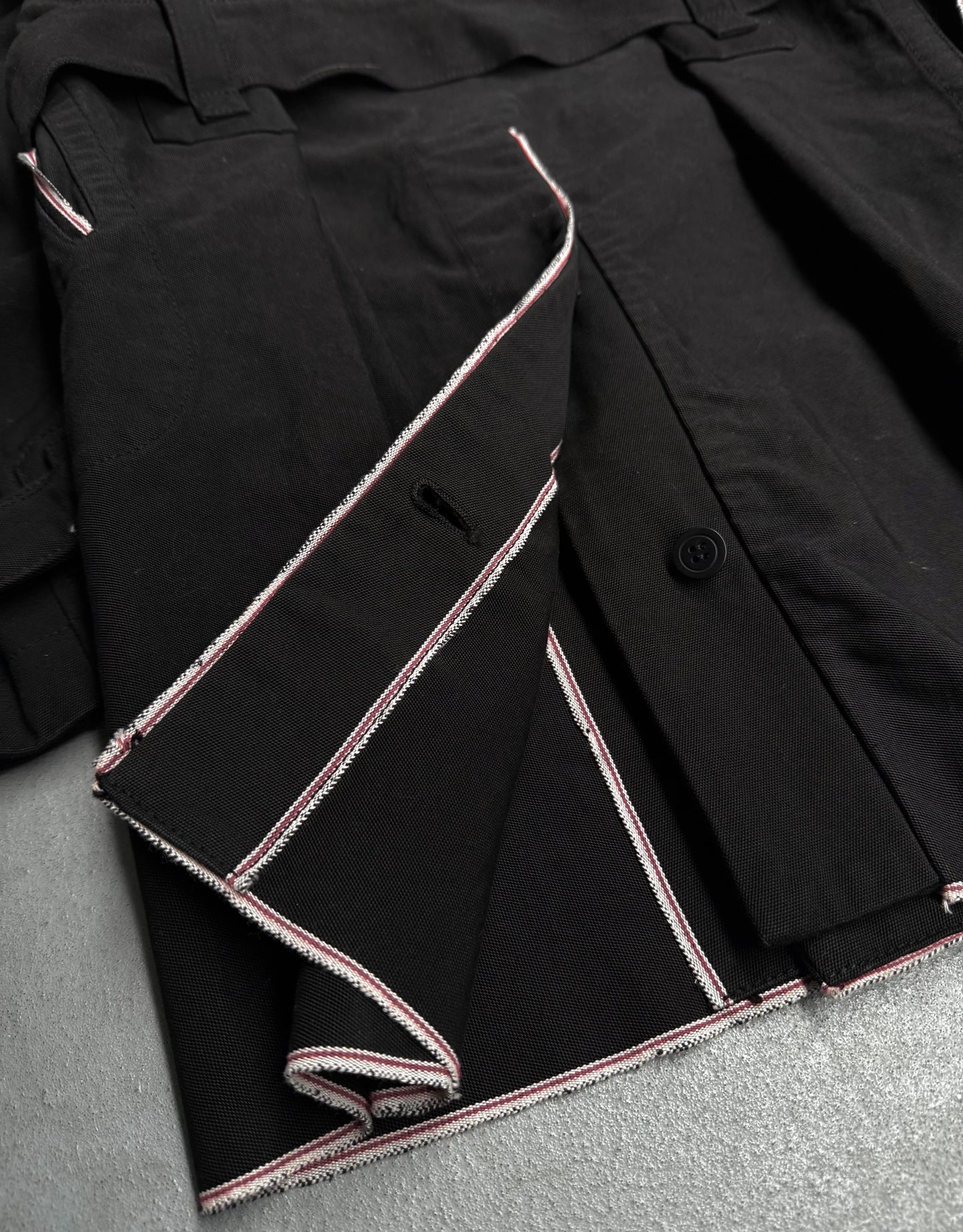Close-up of a black jacket with pink stitching on a gray surface