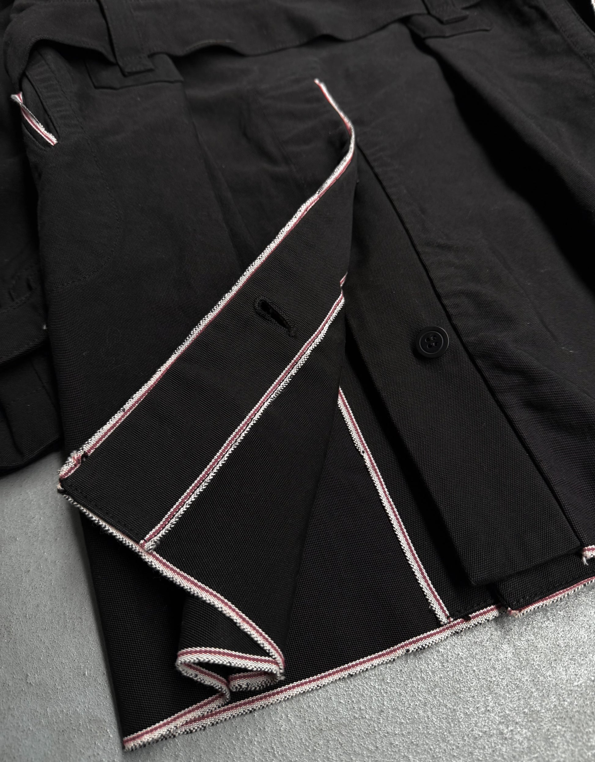 Close-up of a black jacket with pink stitching on a gray surface