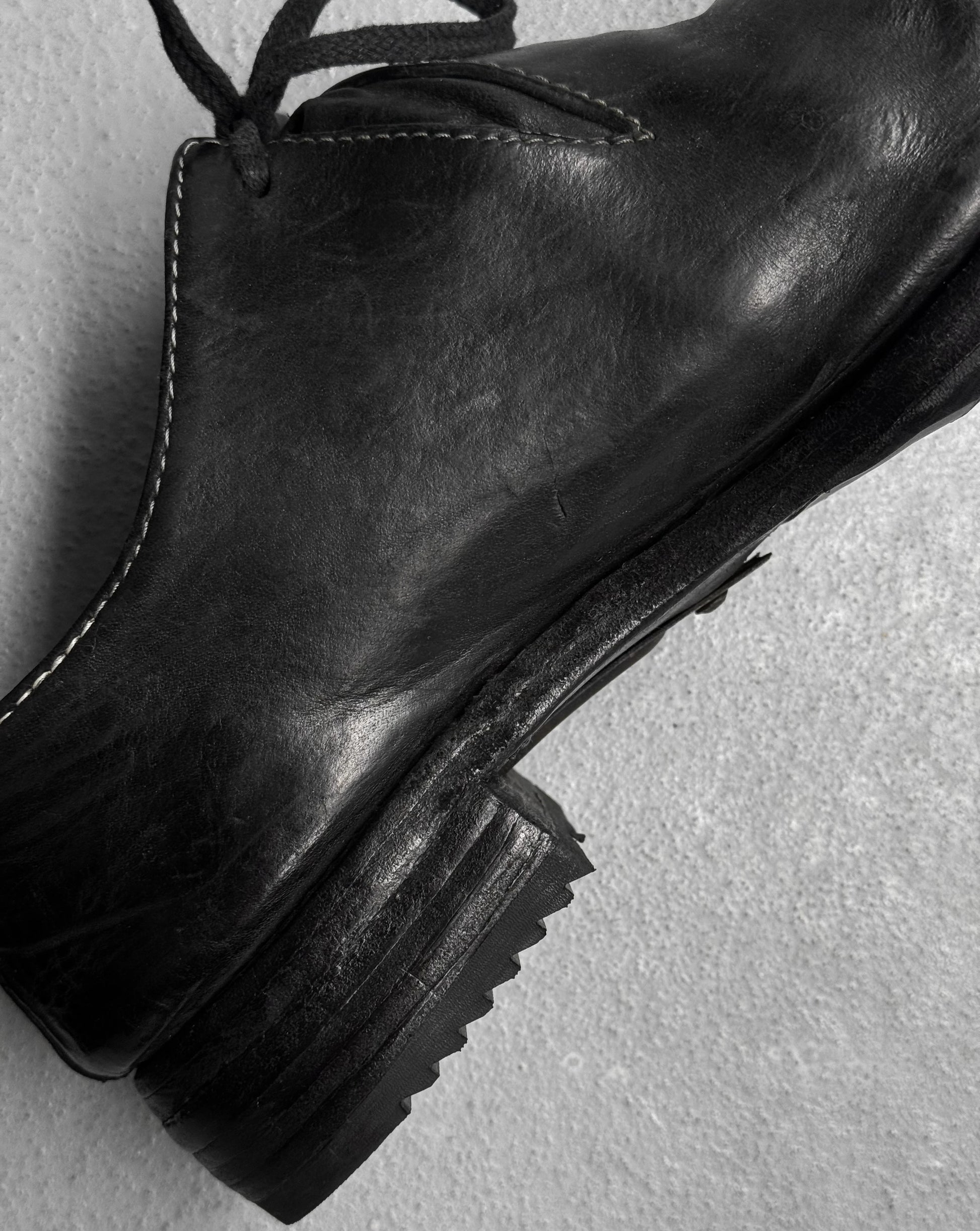 Black leather boot on a light gray background