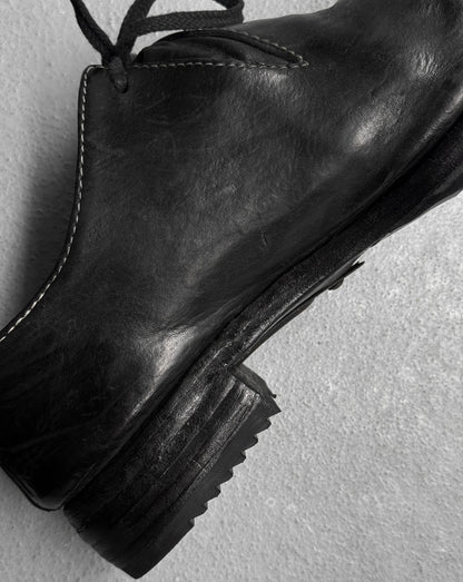 Black leather boot on a light gray background