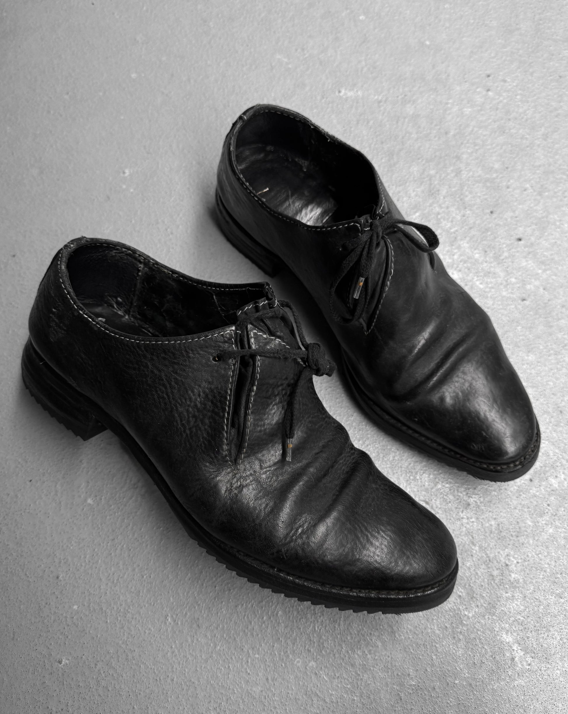 Pair of black leather shoes on a gray concrete surface