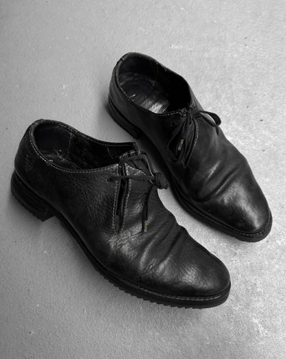 Pair of black leather shoes on a gray concrete surface