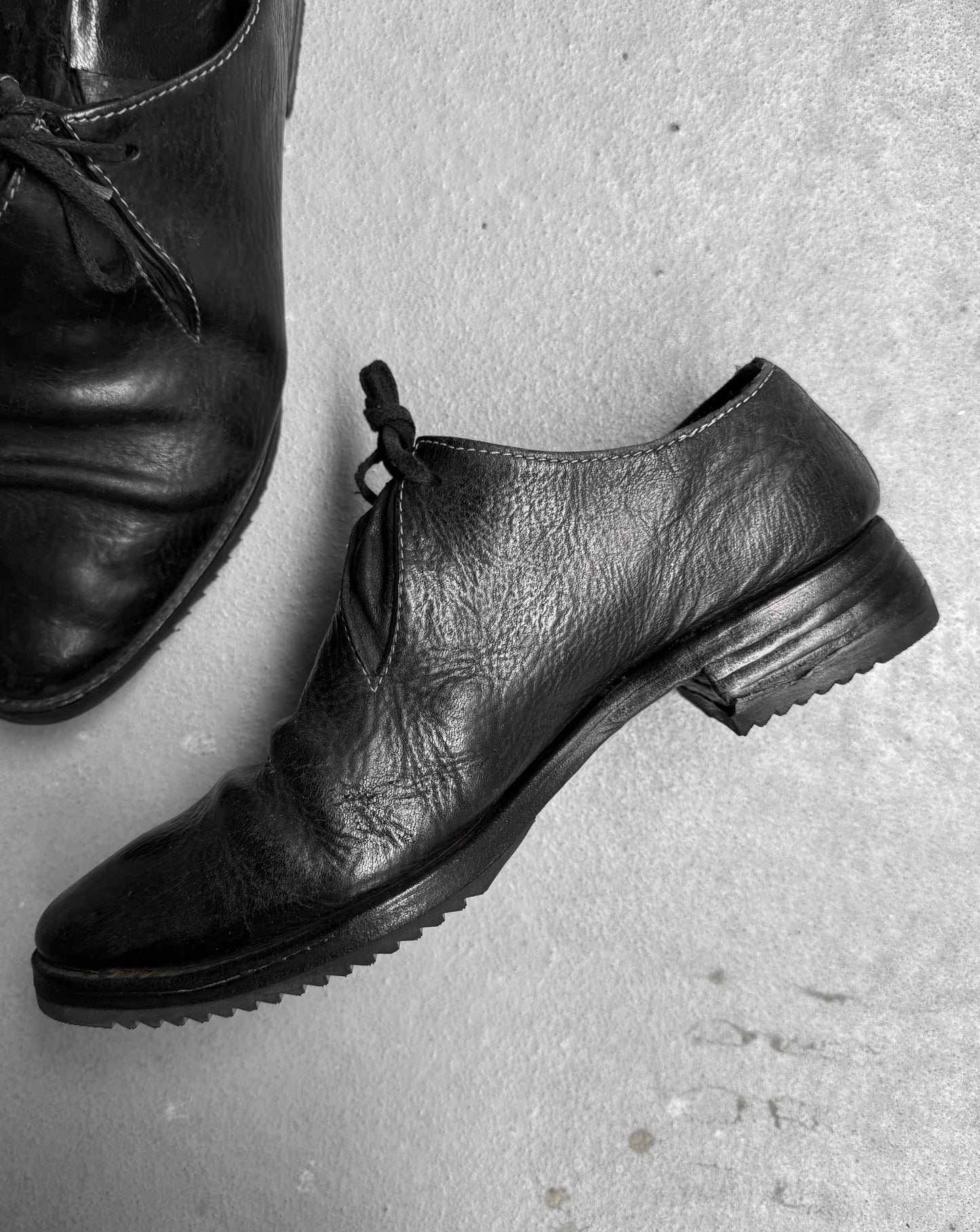 Pair of black leather shoes on a textured surface