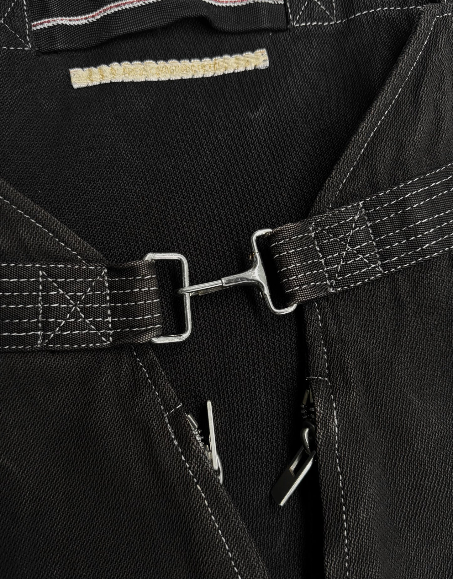 Close-up of black leather harness with metal buckles and stitching details.
