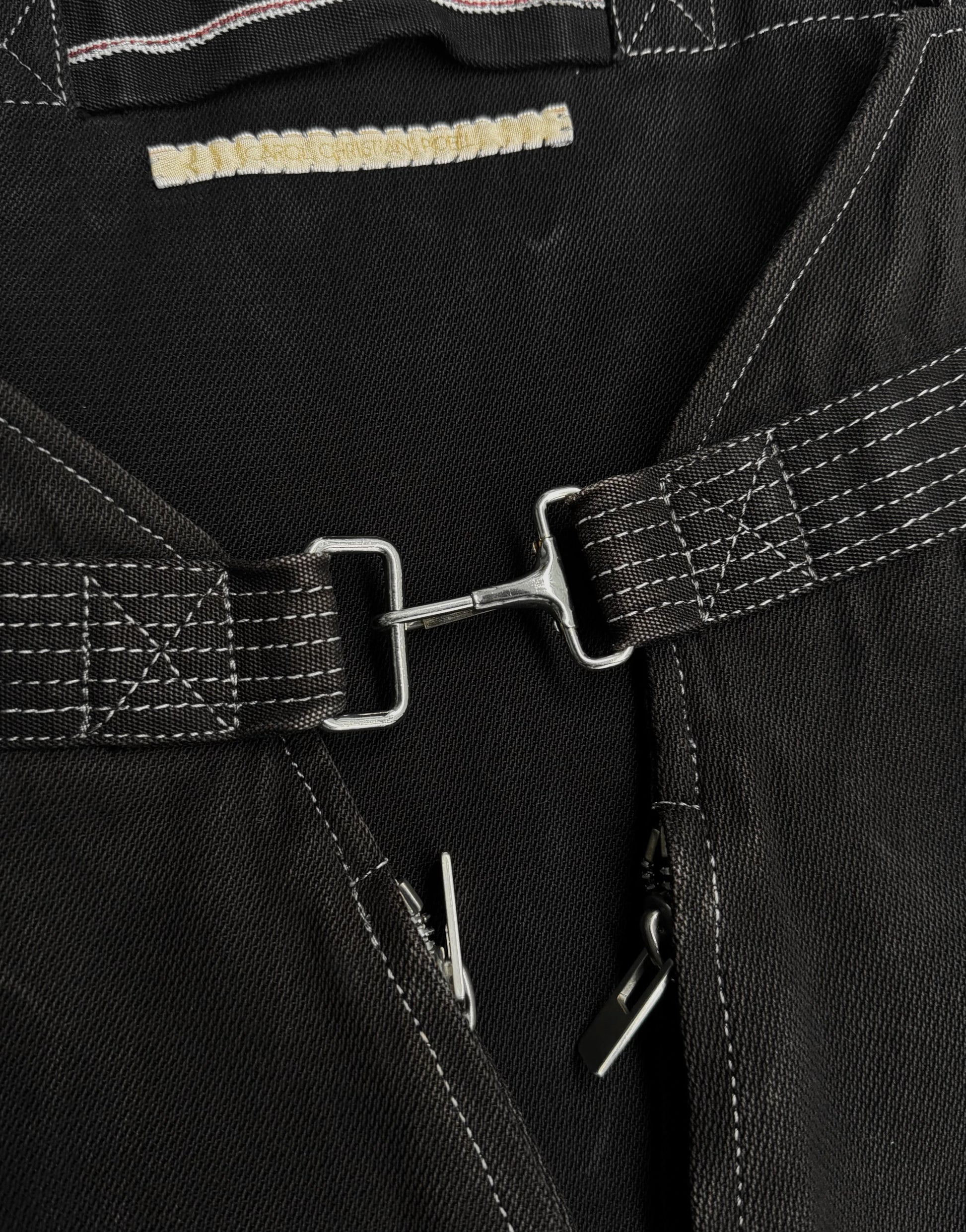 Close-up of black leather harness with metal buckles and stitching details.