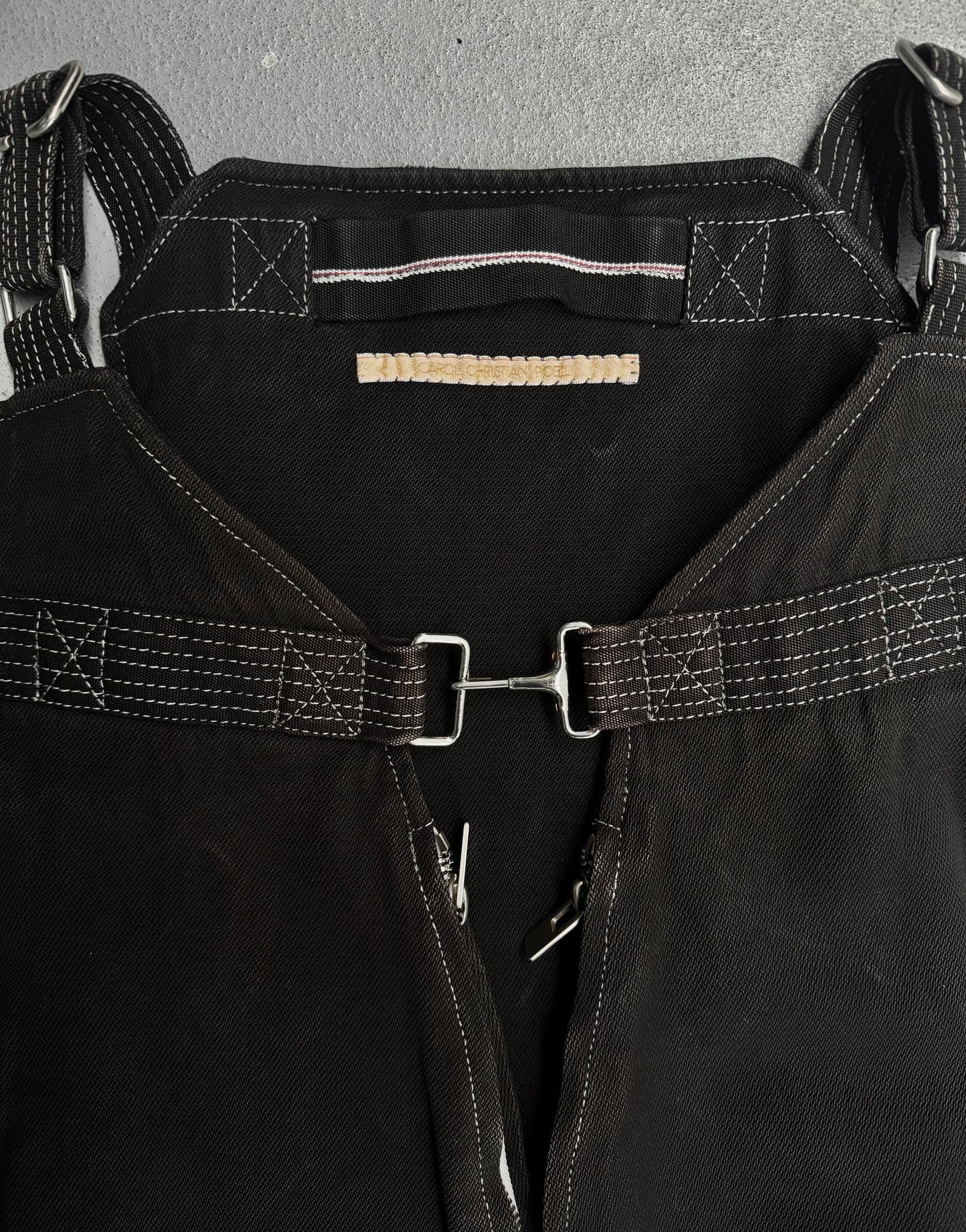 Close-up of a black leather harness with metal buckles on a gray background