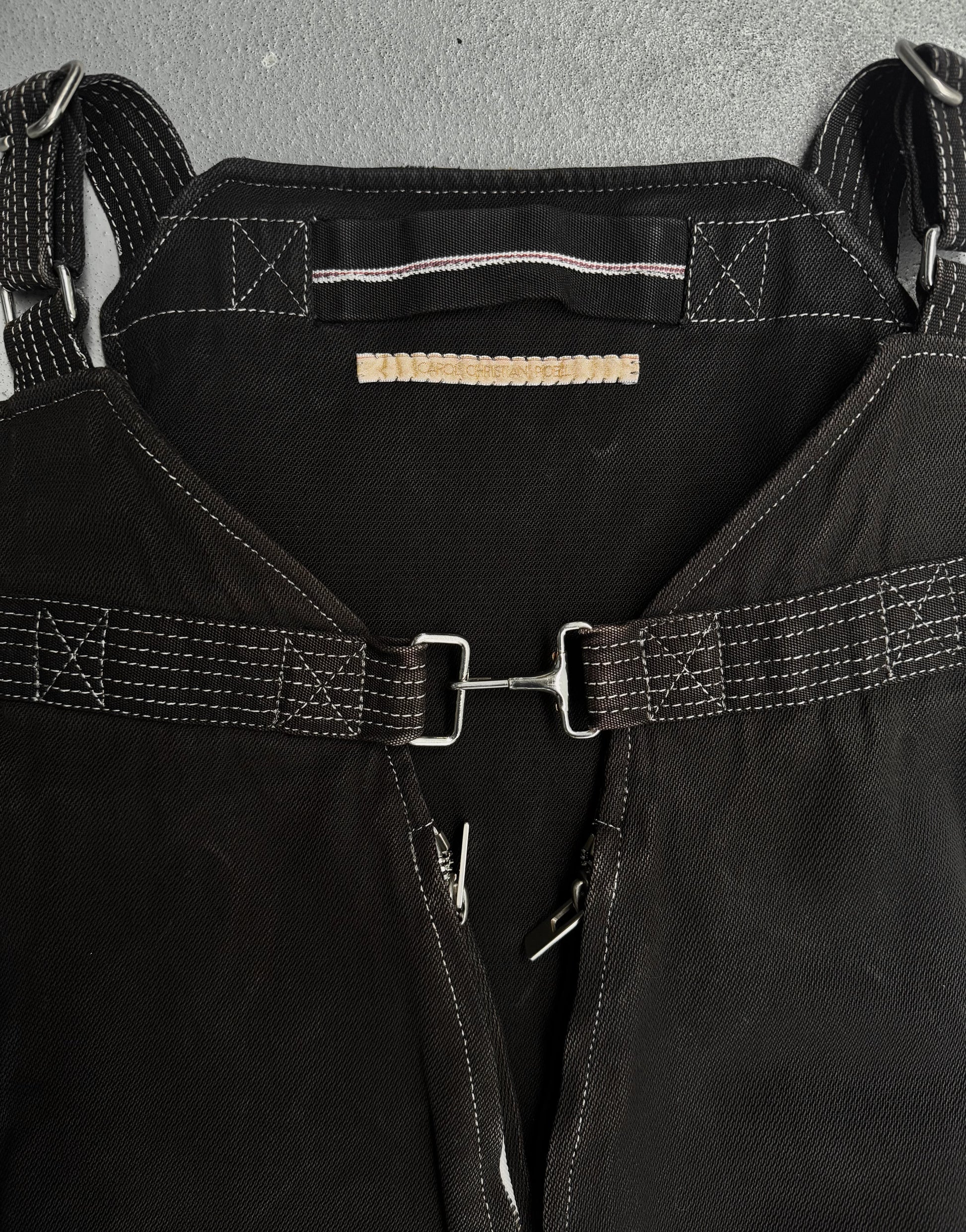 Close-up of a black leather harness with metal buckles on a gray background
