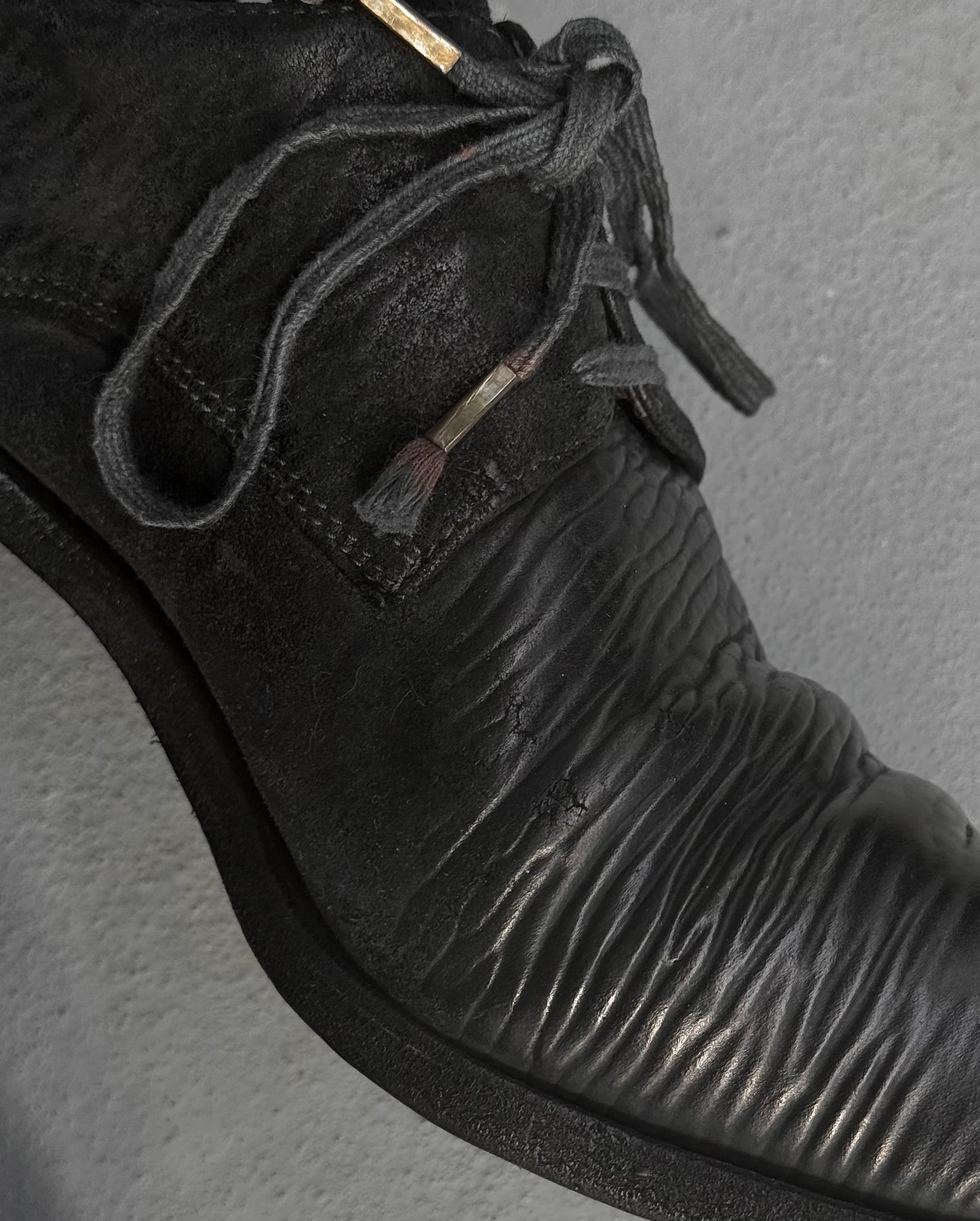 Close-up of a black leather shoe with textured sole on a gray background