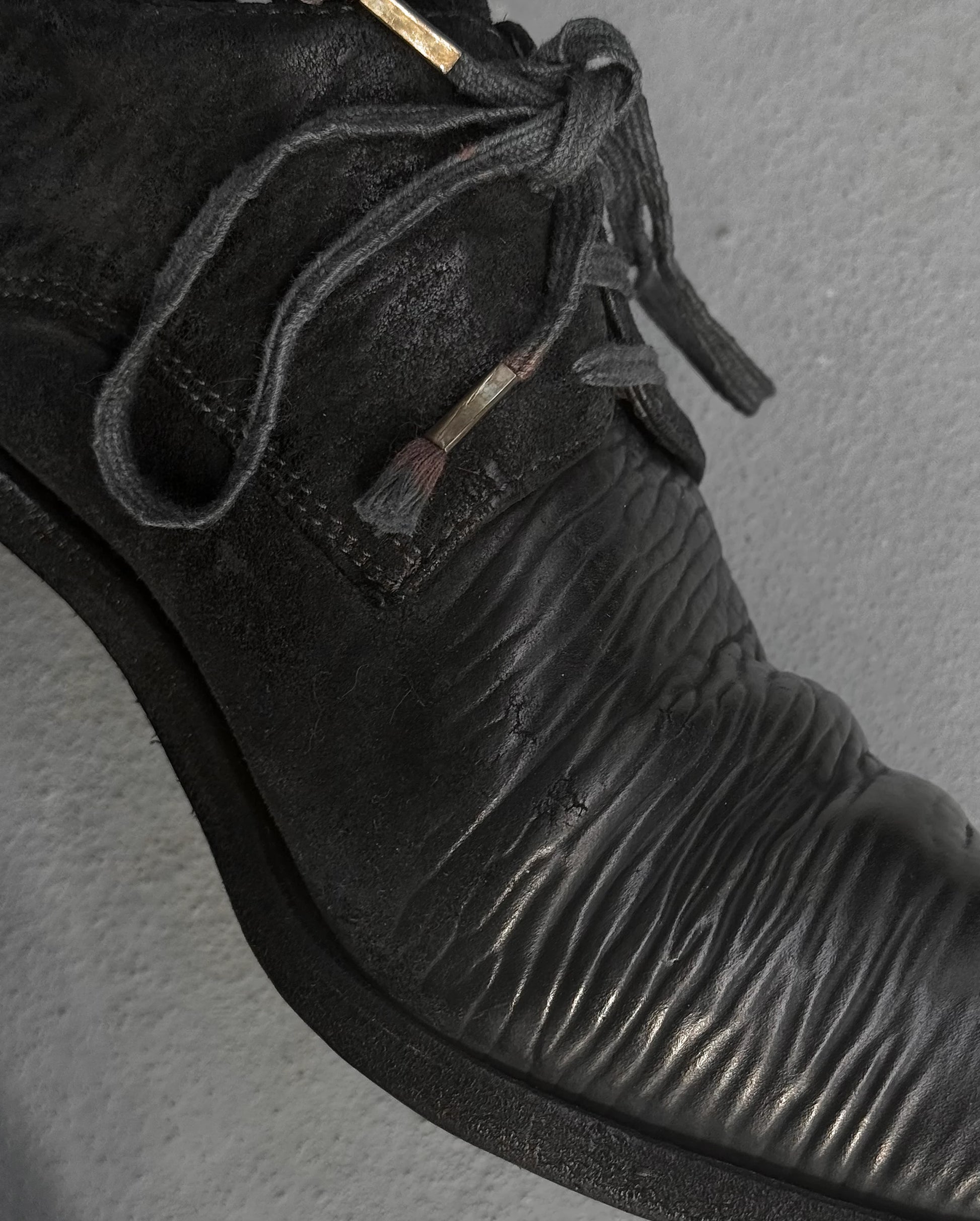 Close-up of a black leather shoe with textured sole on a gray background
