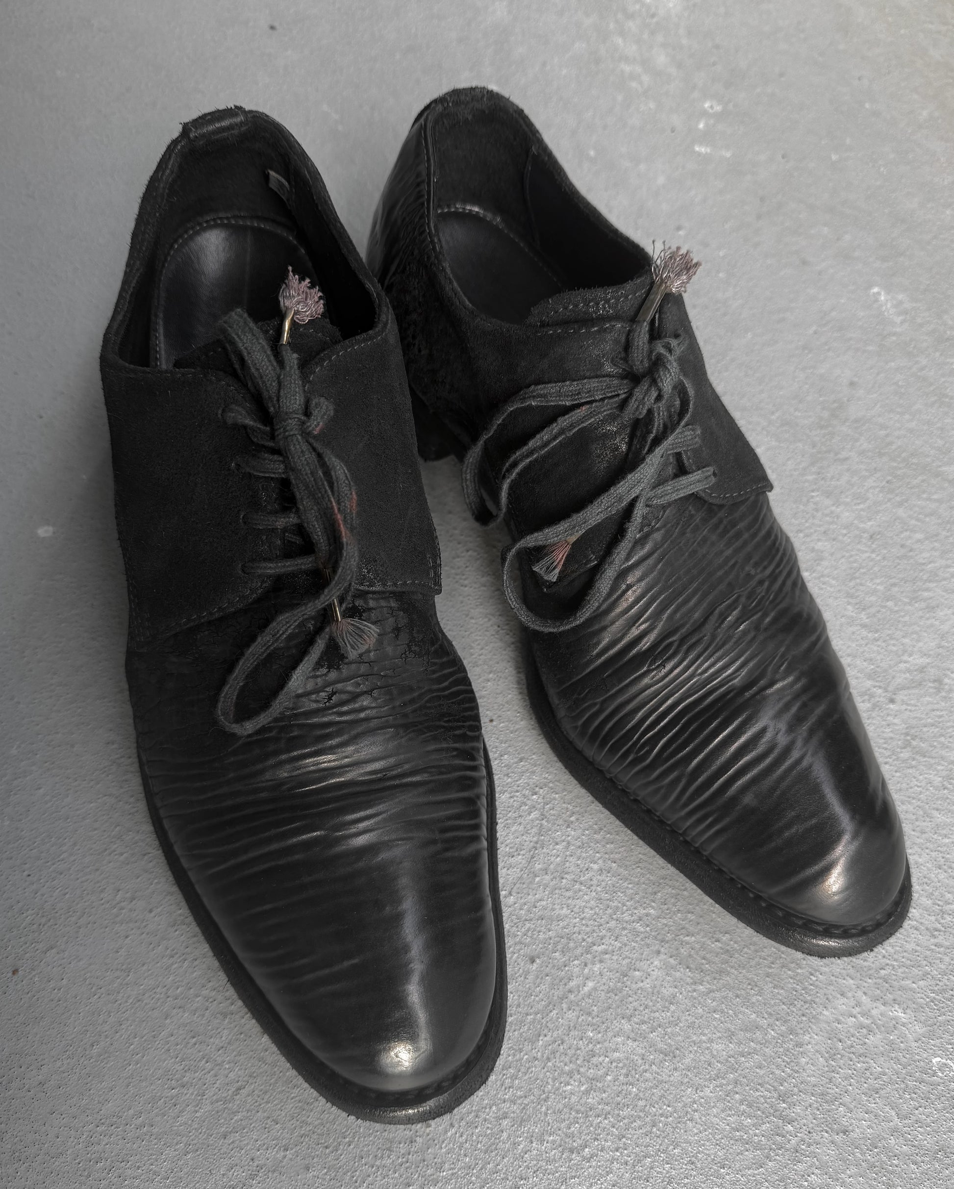 Pair of black leather shoes on a gray surface