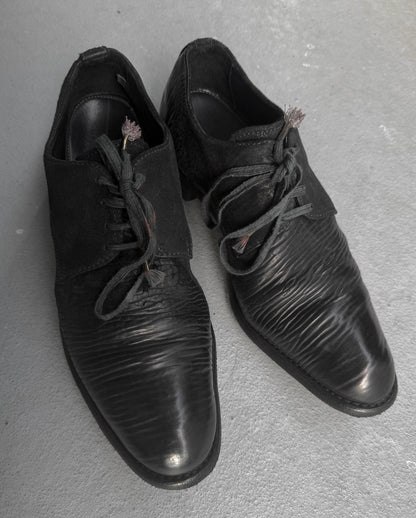 Pair of black leather shoes on a gray surface