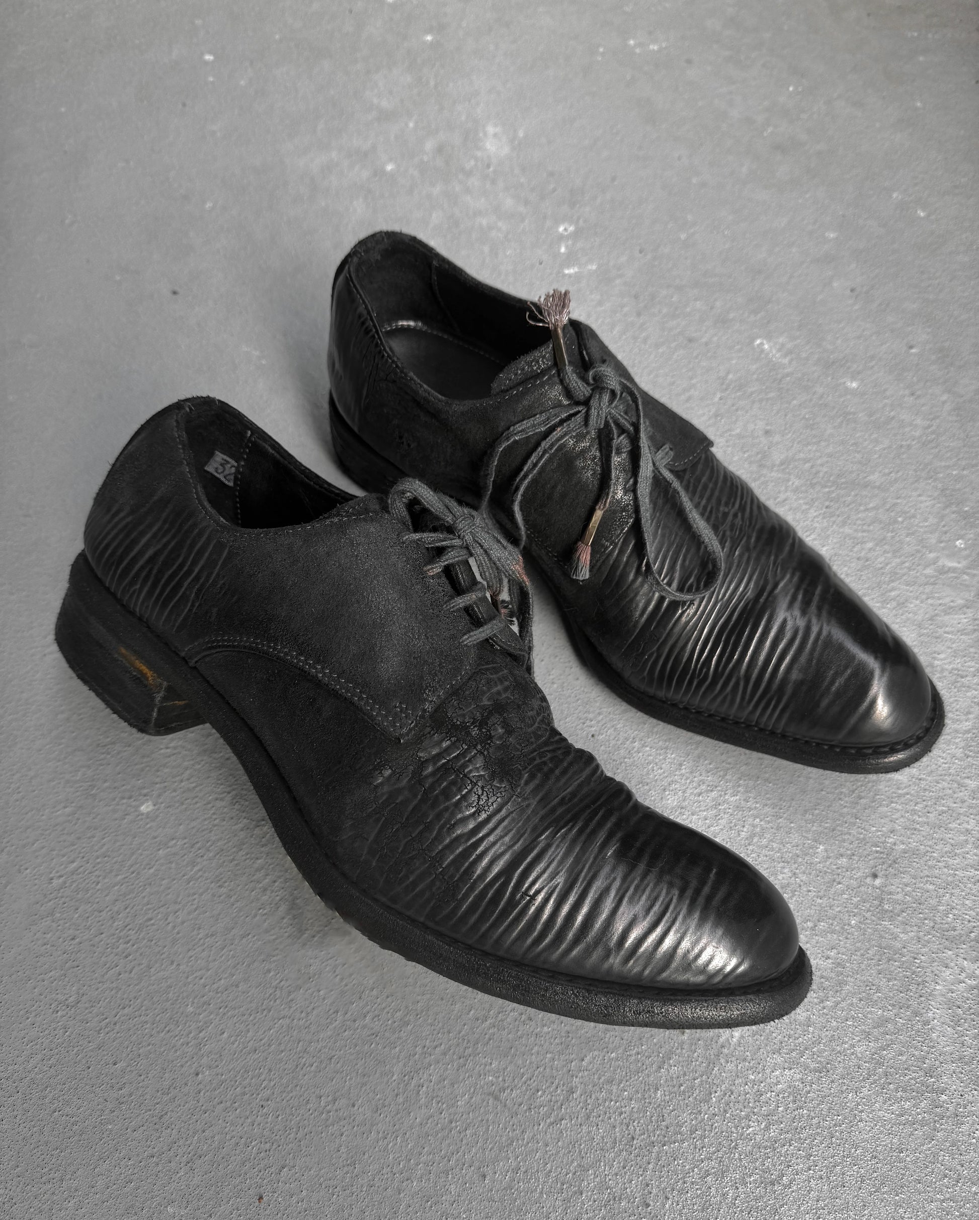 Pair of black dress shoes on a gray surface