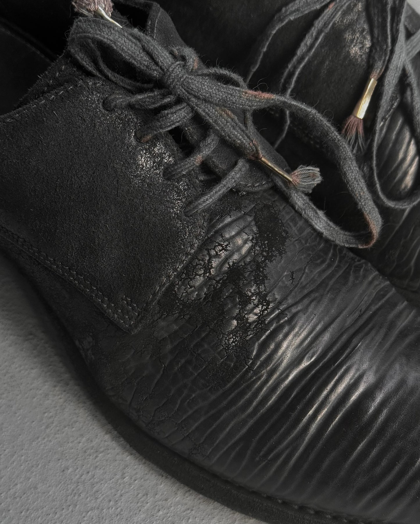 Close-up of a black leather shoe with textured sole and laces.