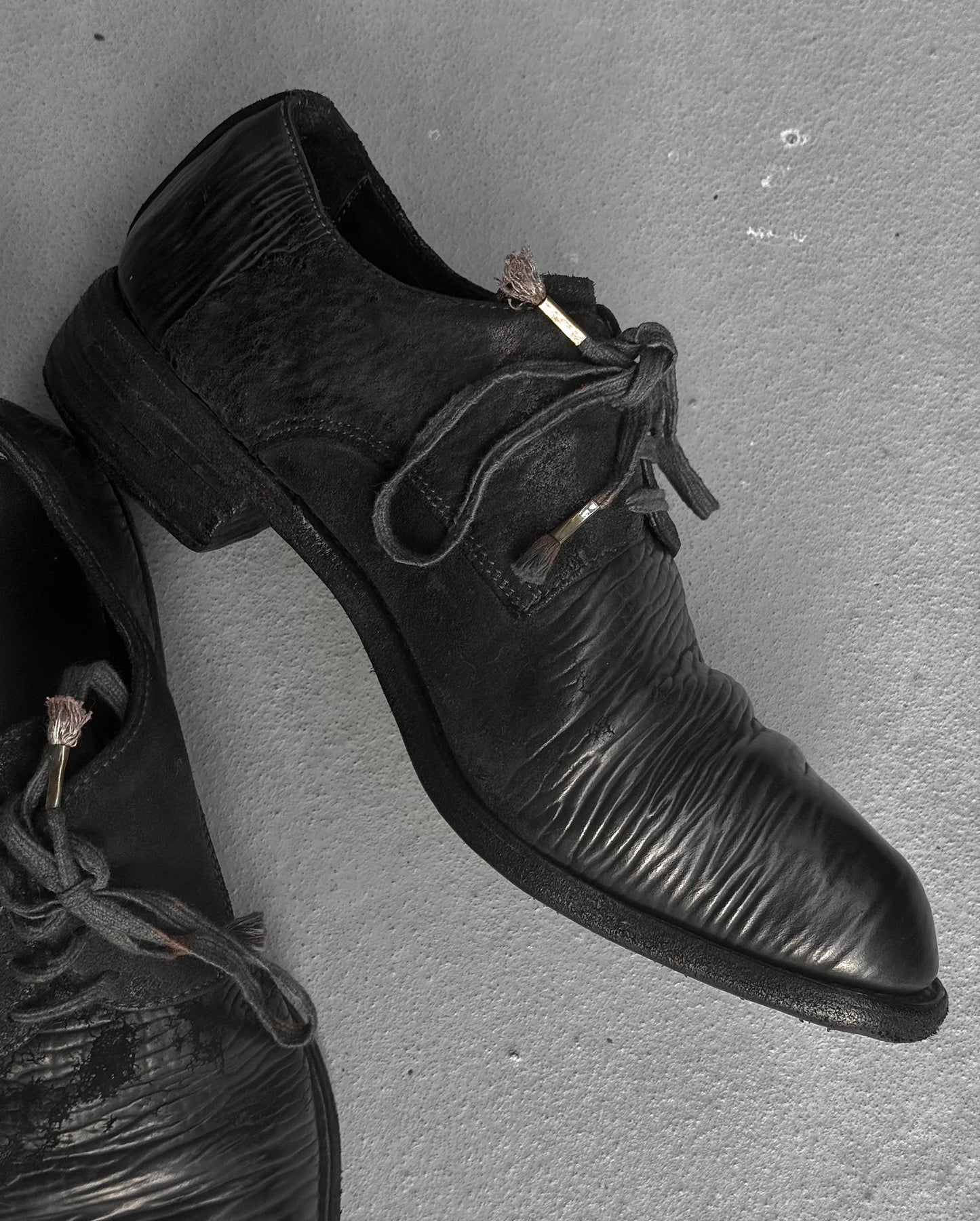 Pair of black leather shoes on a gray surface